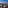 Rooftop bar city view at dusk with mountains, outdoor lounge seating.