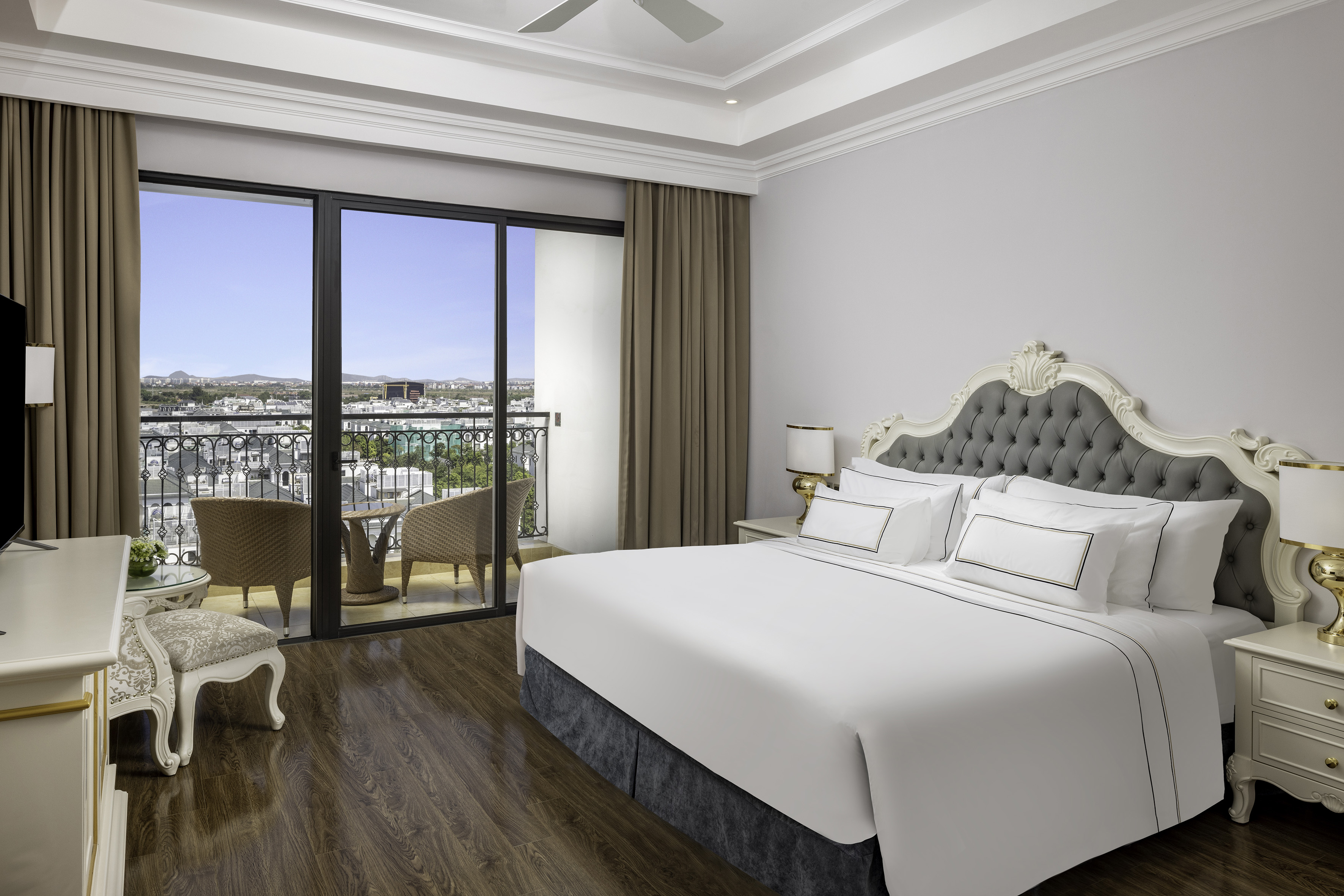Elegant hotel bedroom with balcony, city view, and luxury king bed.