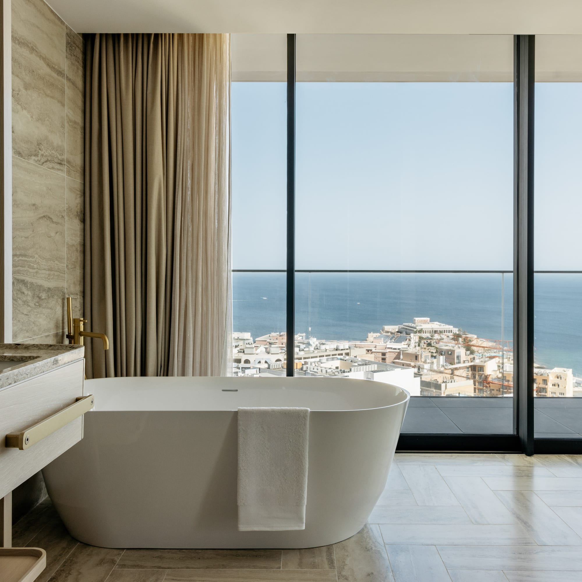 a bathroom with a bathtub and a large window overlooking the ocean