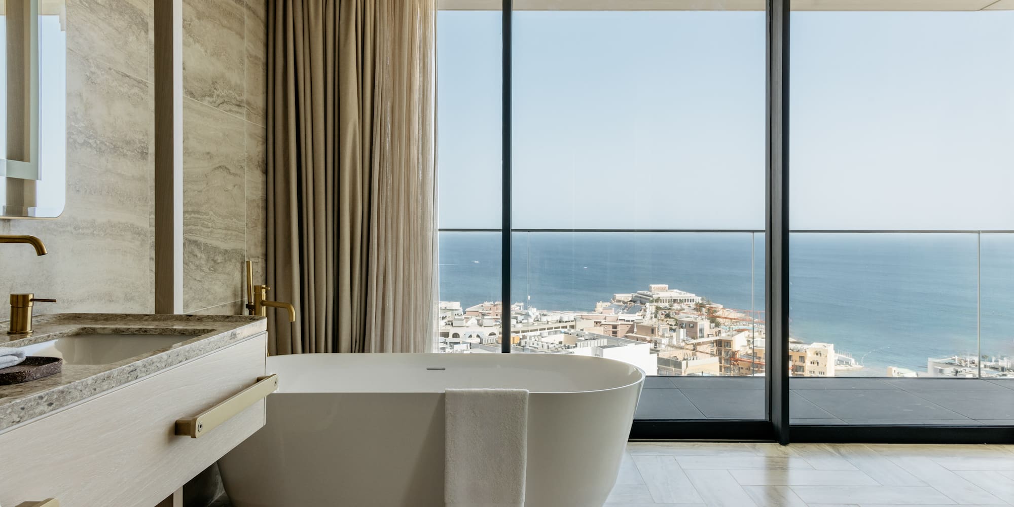 a bathroom with a bathtub and a large window overlooking the ocean