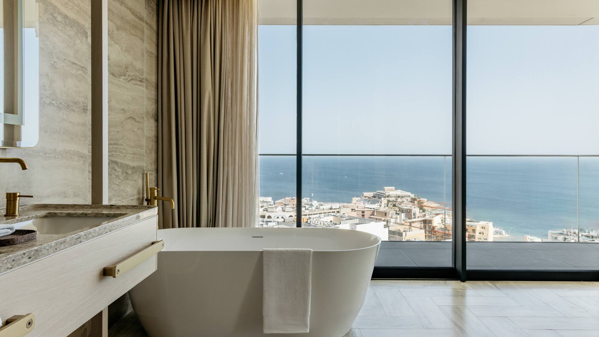 a bathroom with a bathtub and a large window overlooking the ocean