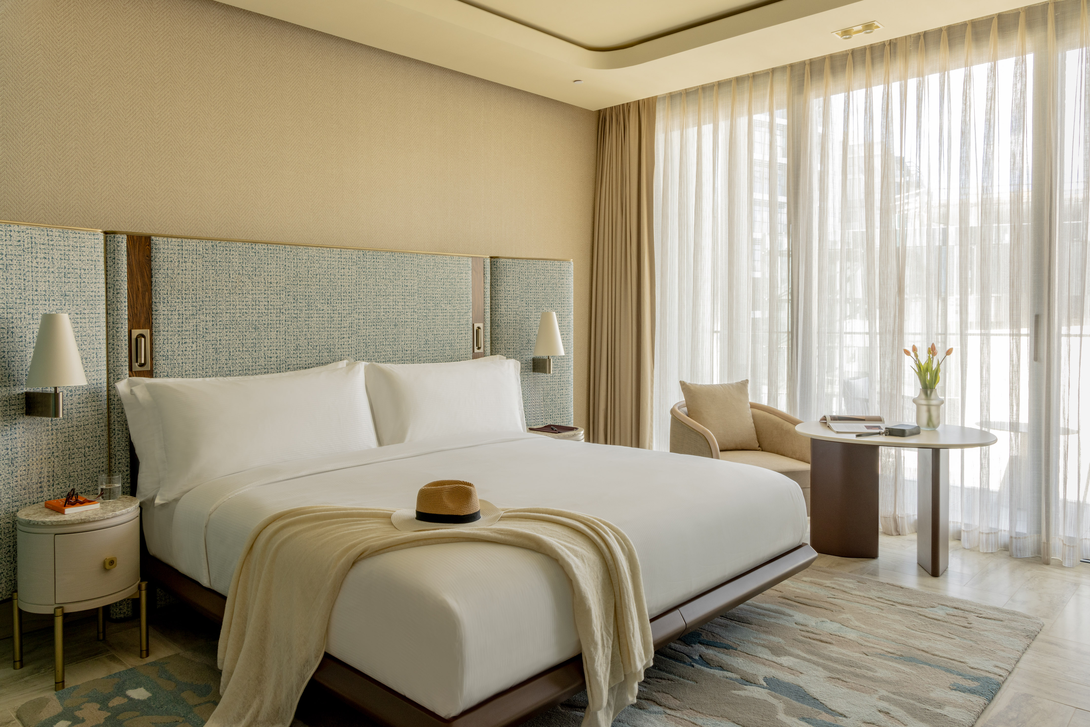 Modern luxury hotel room with king bed, elegant design, and sunlit window.