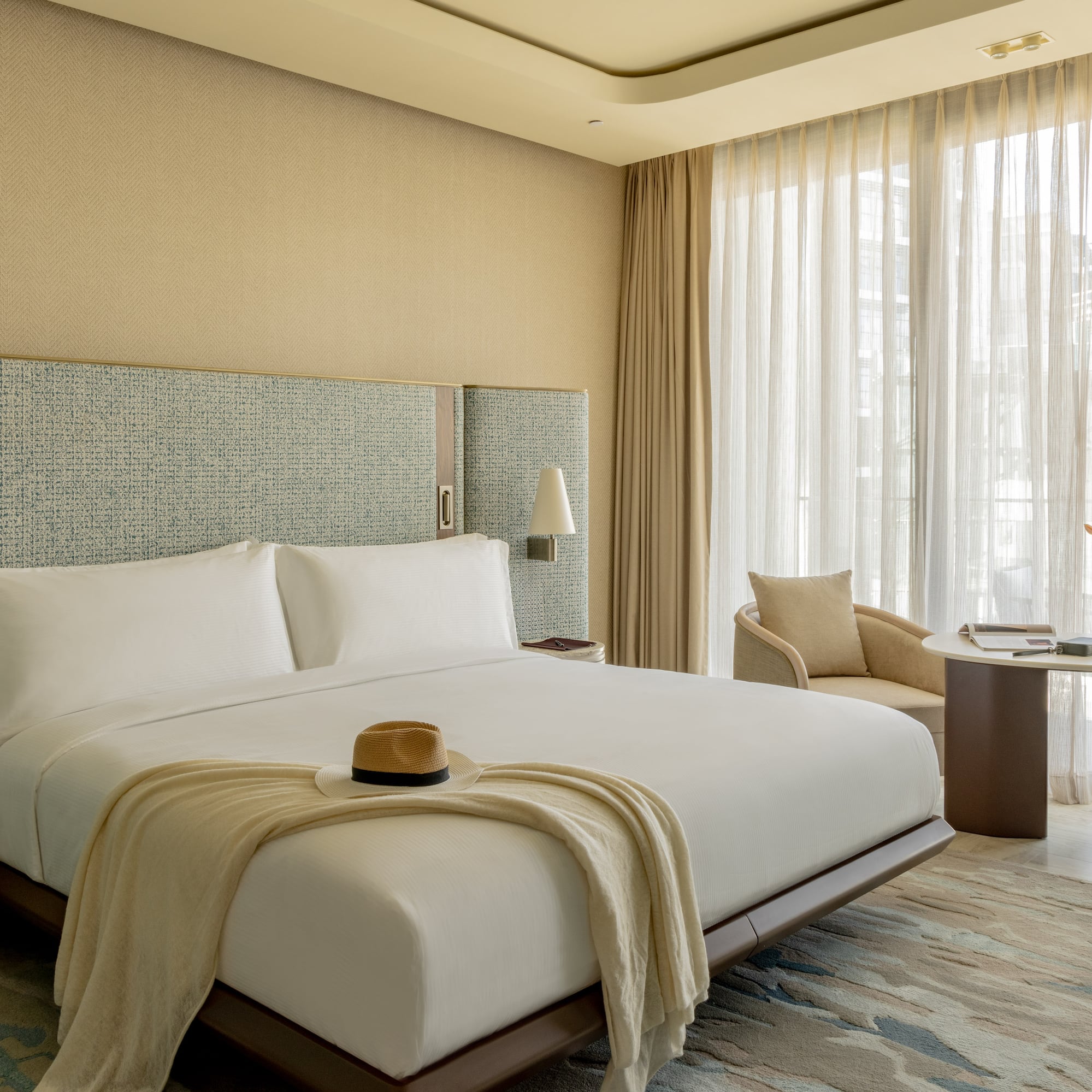 Modern luxury hotel room with king bed, elegant design, and sunlit window.