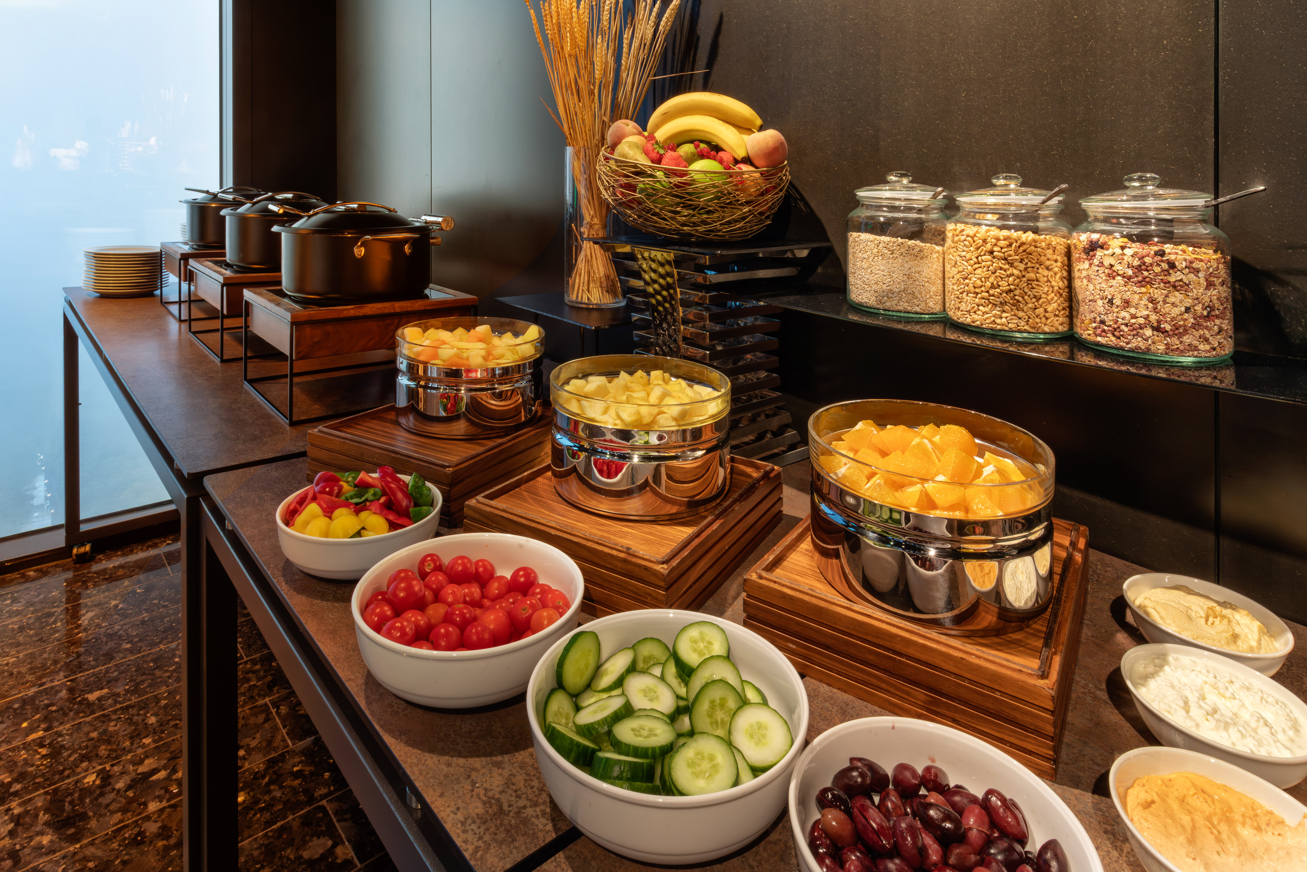 Modern hotel buffet with fresh fruit, vegetables, hot food, cereals, and dips.