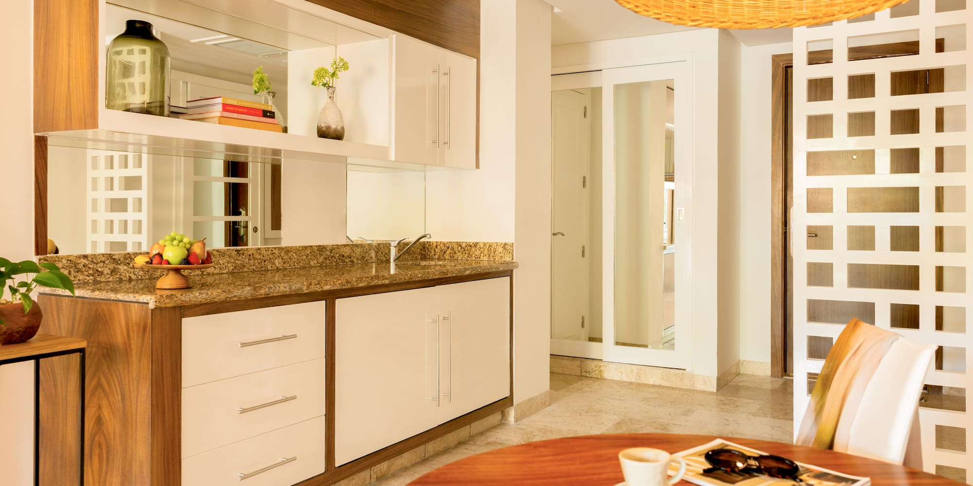 Modern kitchenette and dining area with granite counter and wood cabinets.