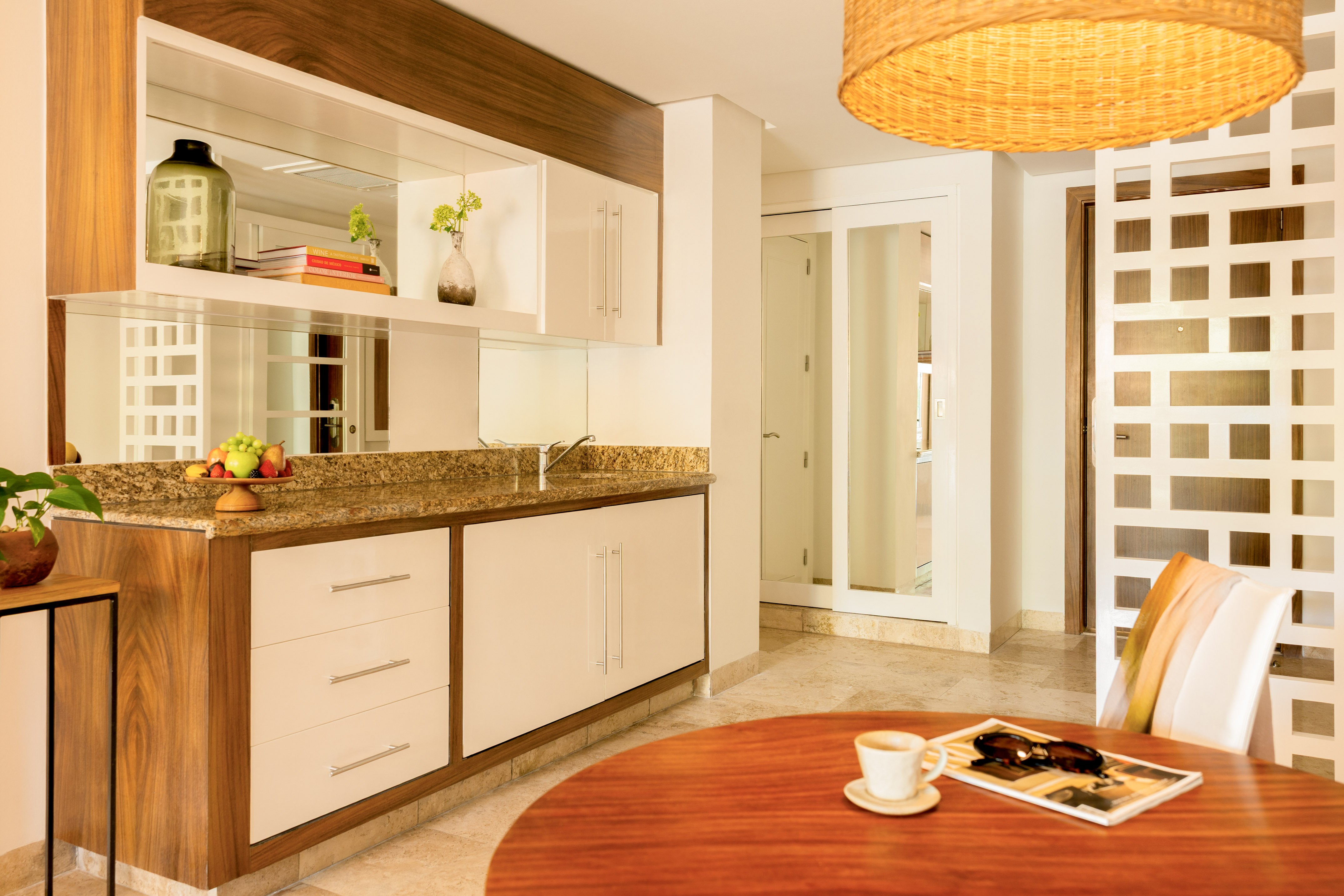 Modern kitchenette and dining area with granite counter and wood cabinets.