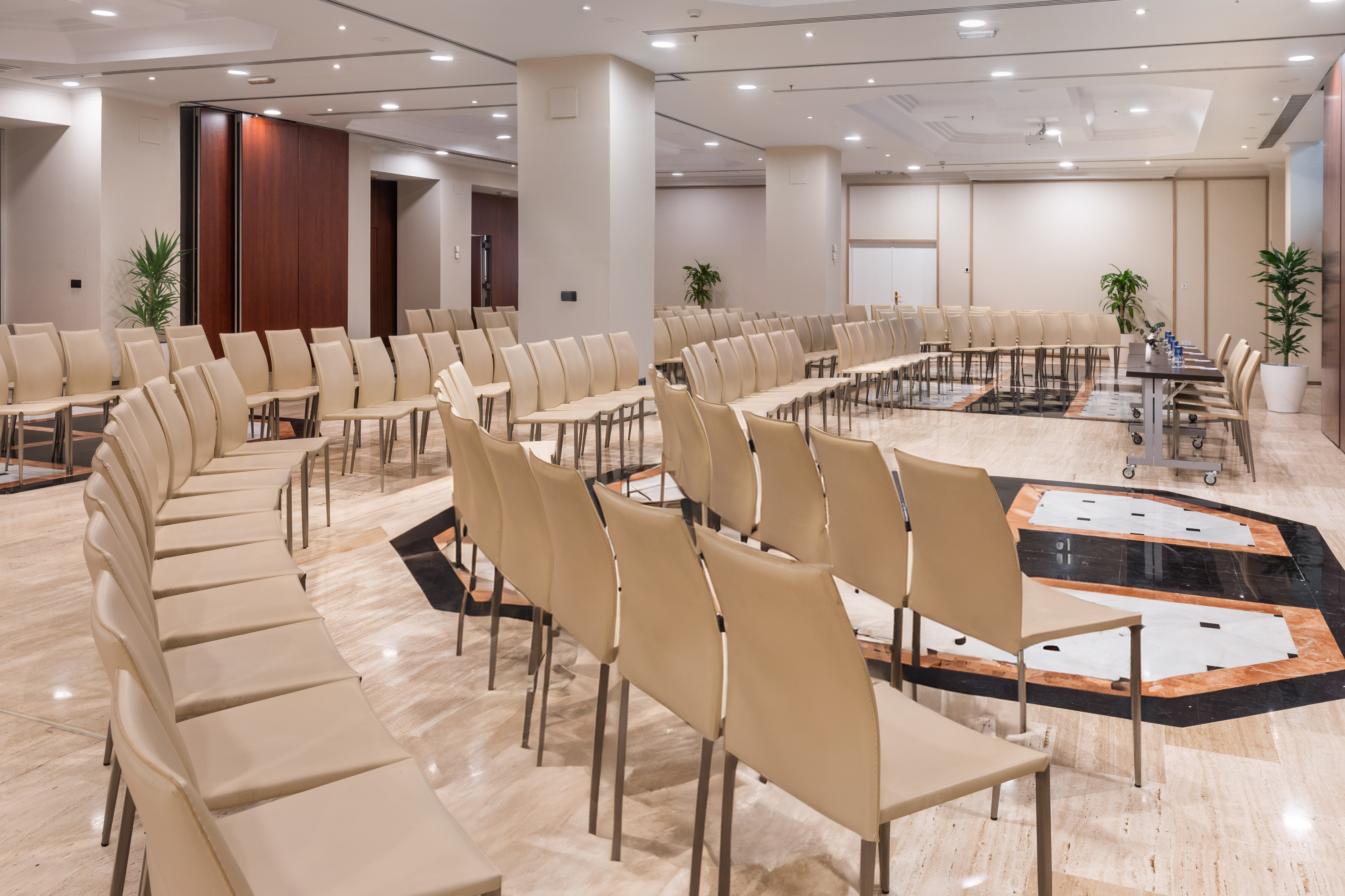 Modern meeting room setup with beige chairs and patterned marble floor.