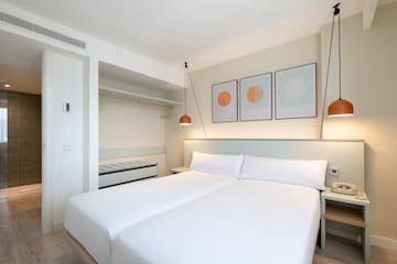 a bed with white sheets and lamps