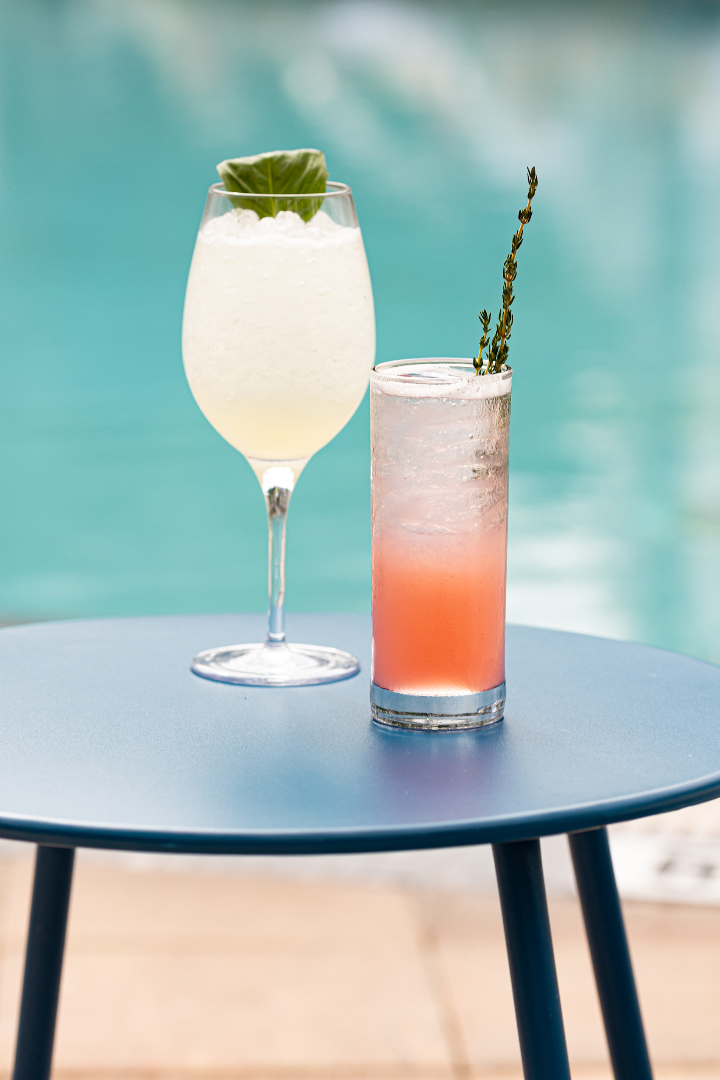 Poolside cocktails: yellow basil drink and pink thyme drink on a blue table. - The Wilson, Cozinha internacional - Meliá Orlando Celebration, Orlando