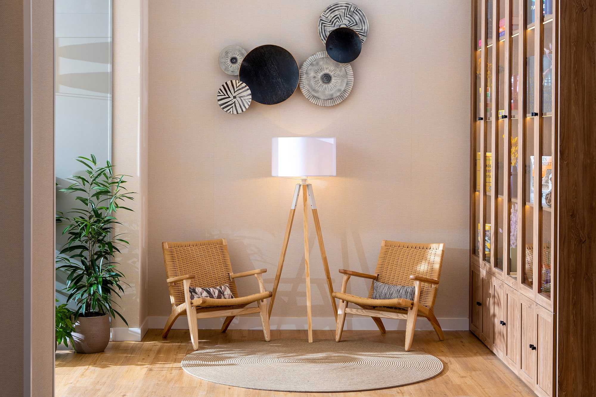Woven accent chairs, tripod floor lamp, and abstract circular wall art.