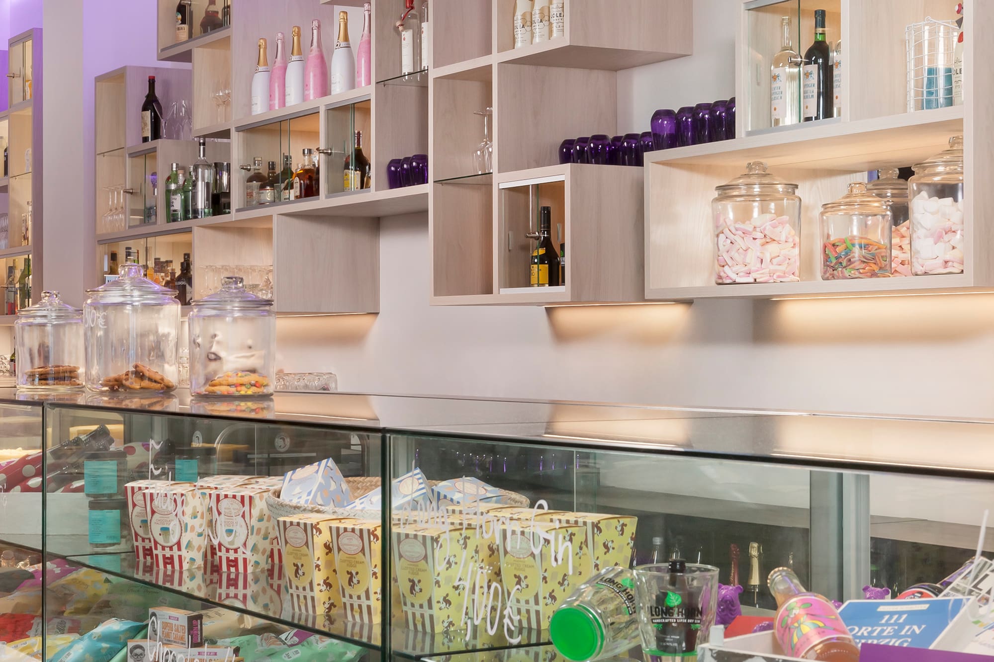Modern shop interior with illuminated shelves, candy jars, and glass display.
