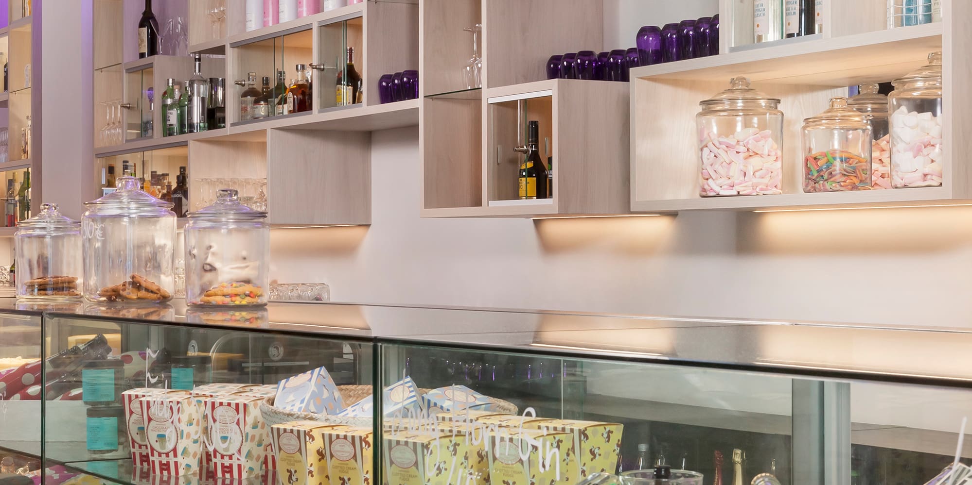 Modern store interior with lighted shelves, drinks, candy, and glass display counter.