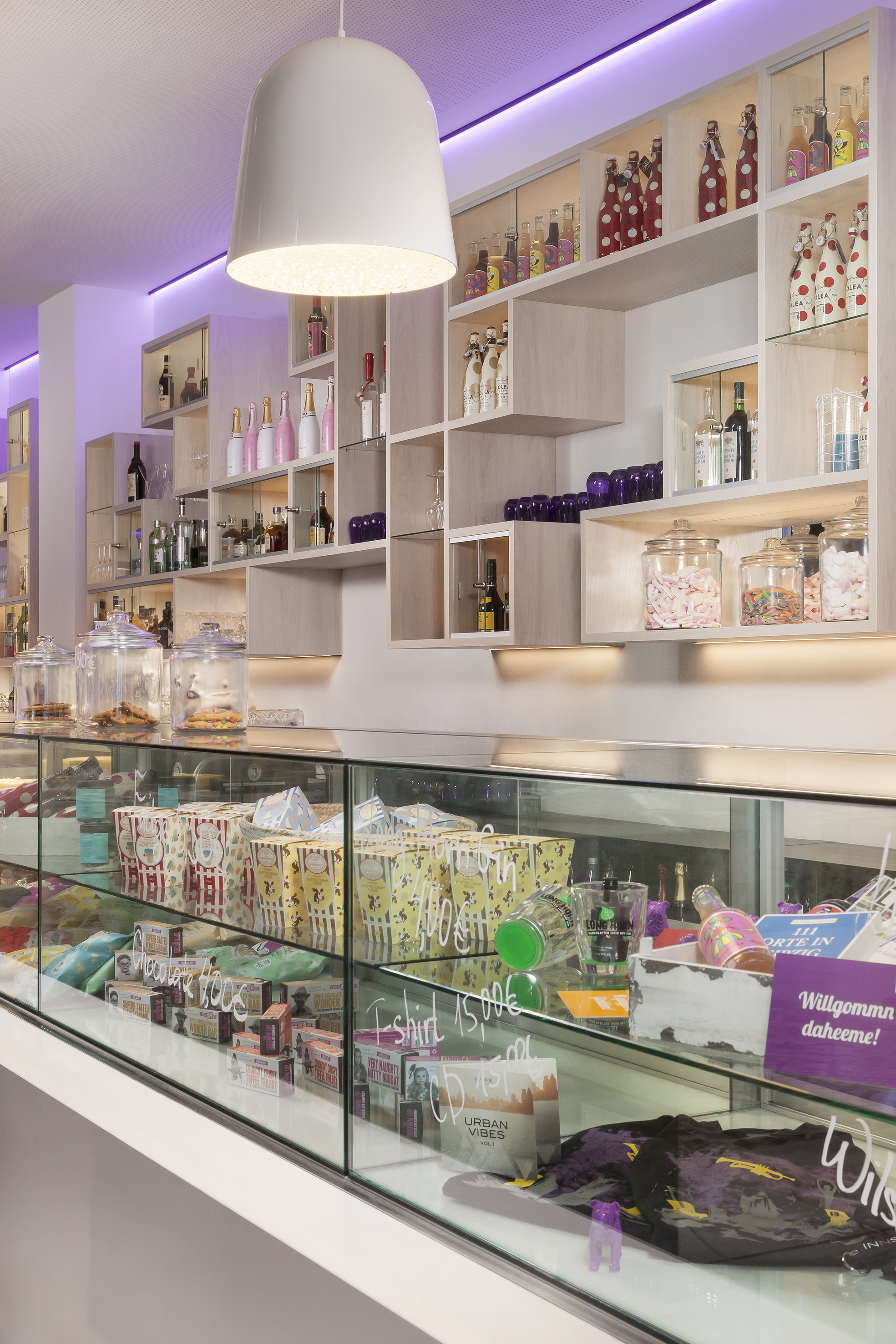 Modern store interior with lighted shelves, drinks, candy, and glass display counter.