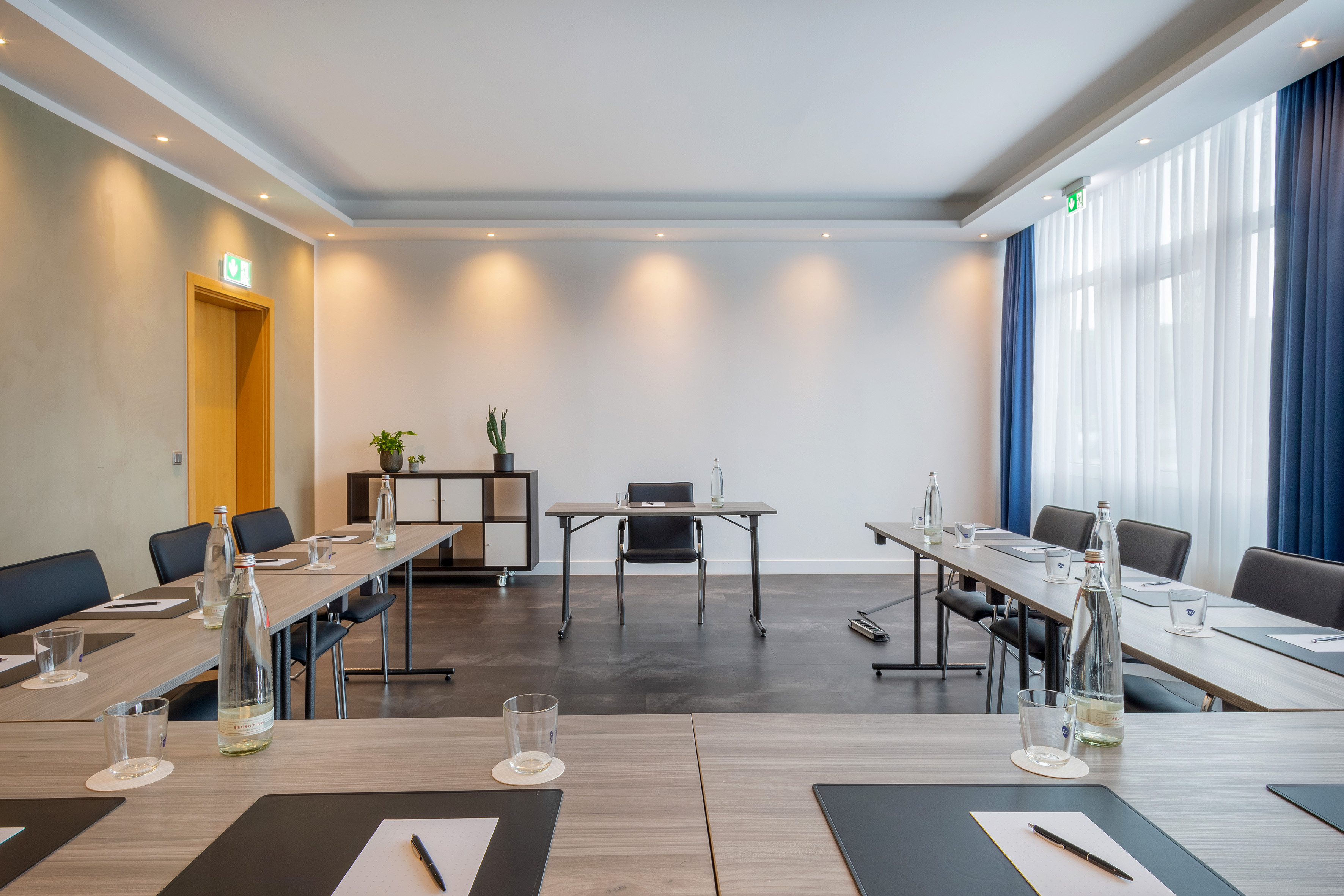 Modern conference room with U-shaped table setup, chairs, and natural light.