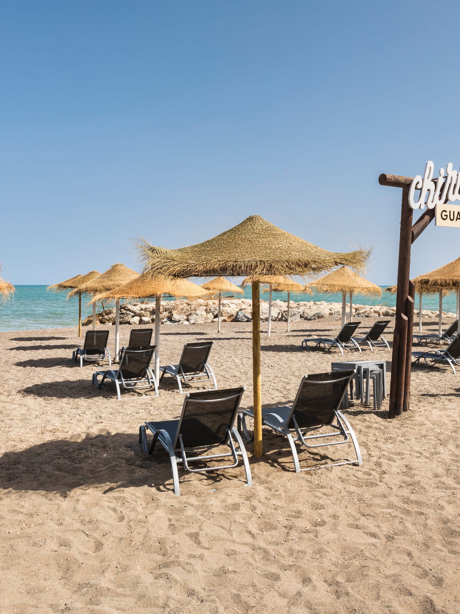 Guadalmar beach, straw umbrellas, sunbeds, ocean, and Chiringuito sign.