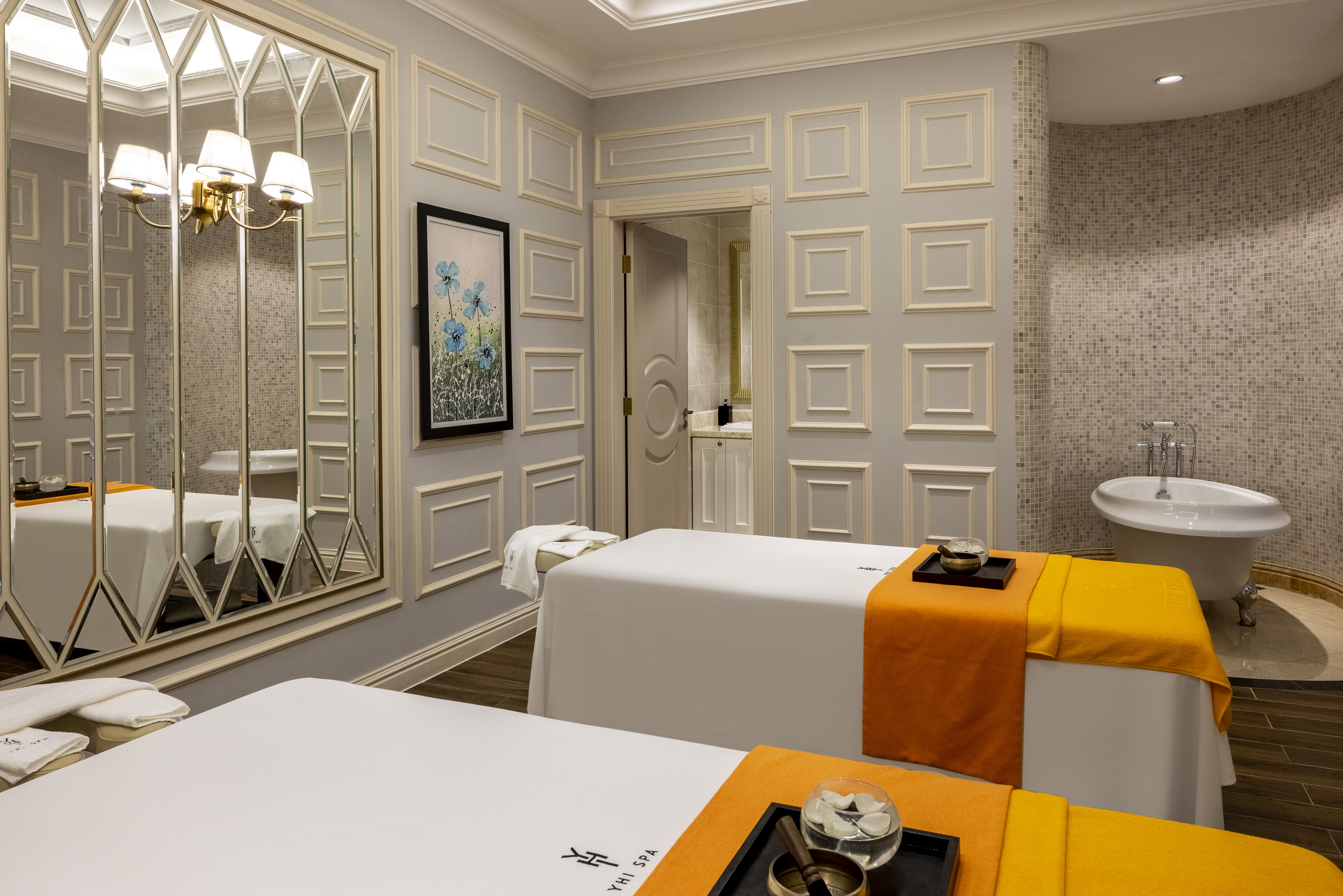Elegant spa treatment room with twin massage tables and freestanding bathtub.