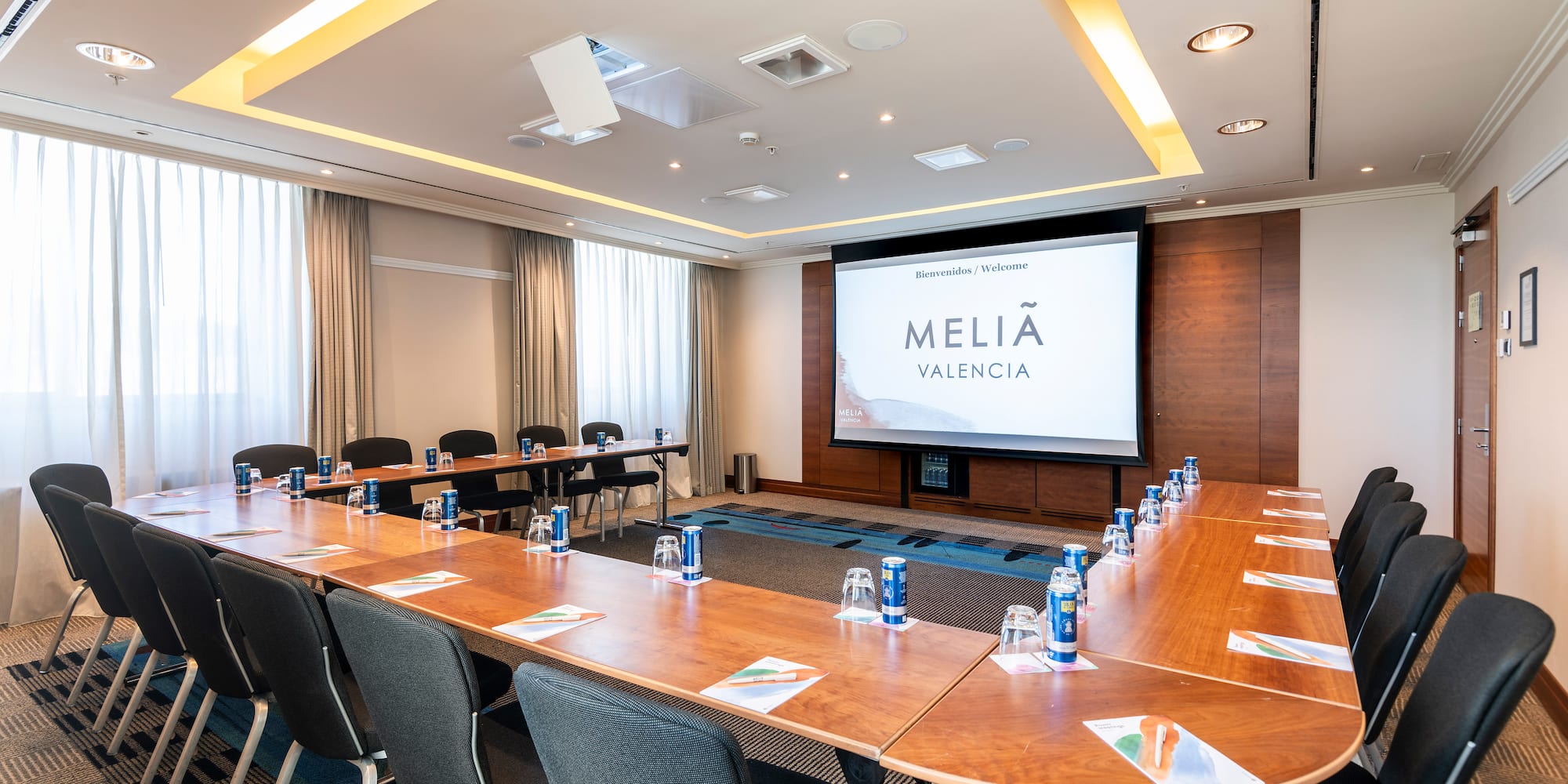 a room with a large screen and tables