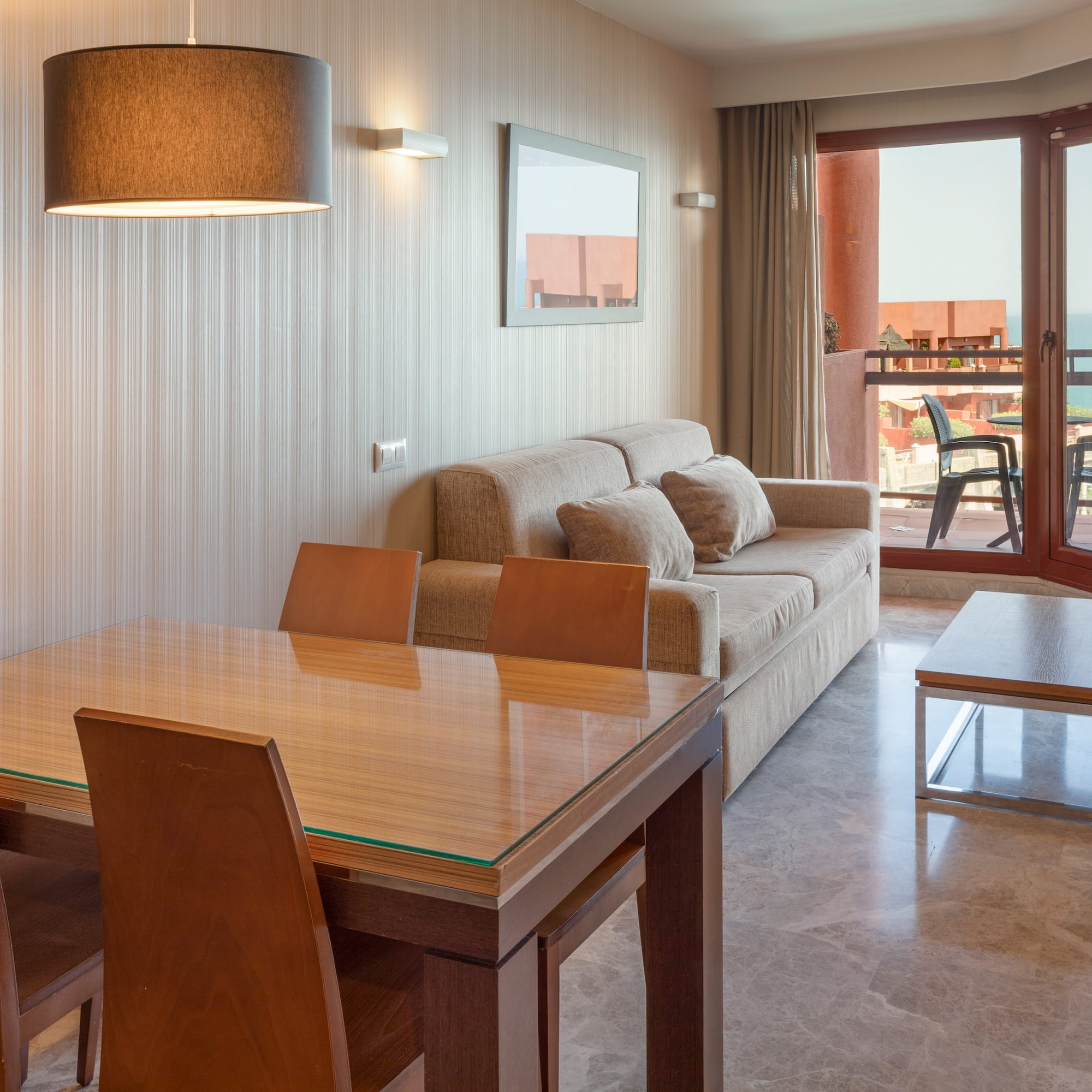Apartment living room with dining table, sofa, and ocean view balcony.
