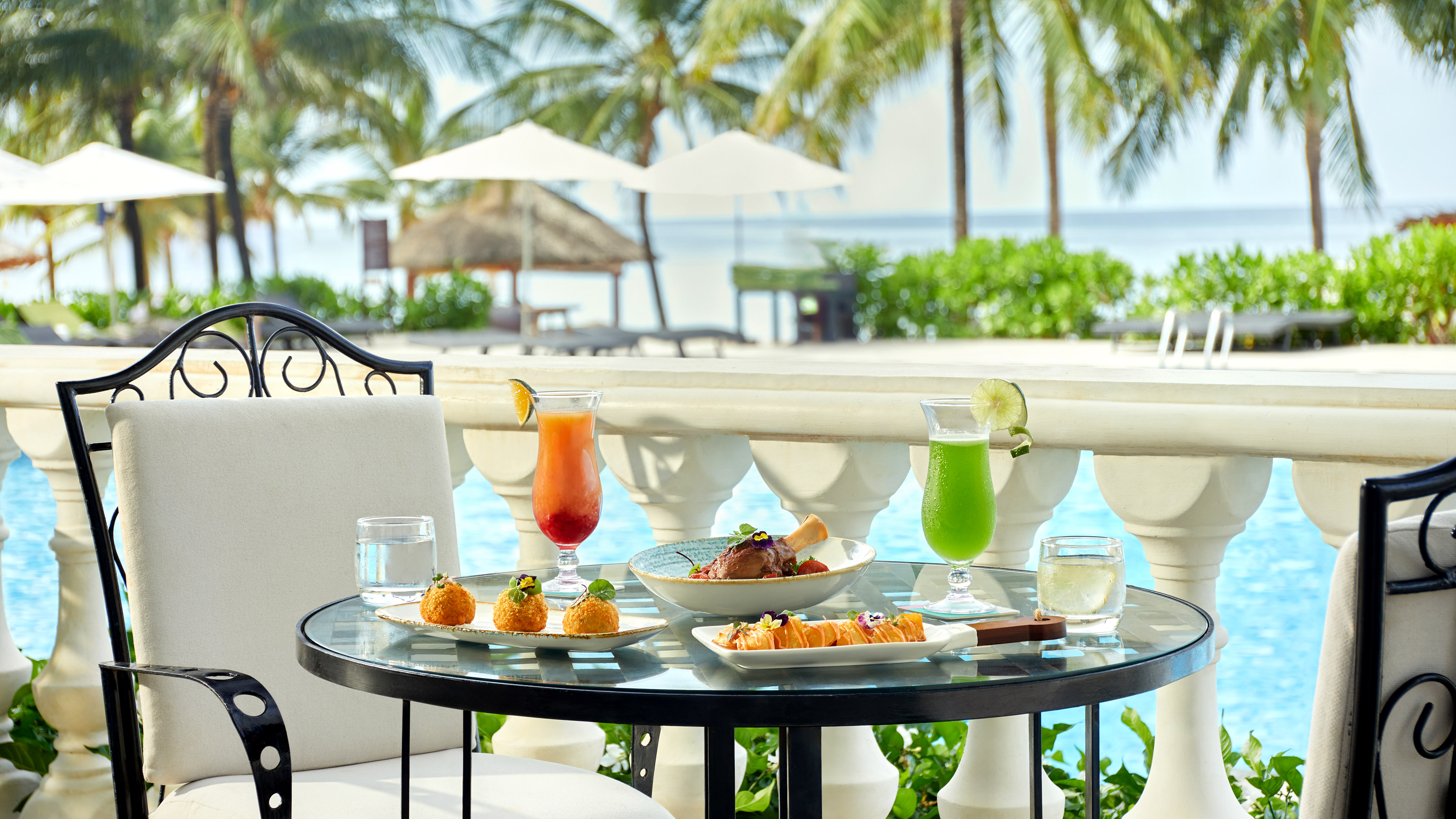 Luxury poolside dining with gourmet food, cocktails, palm trees, ocean view.