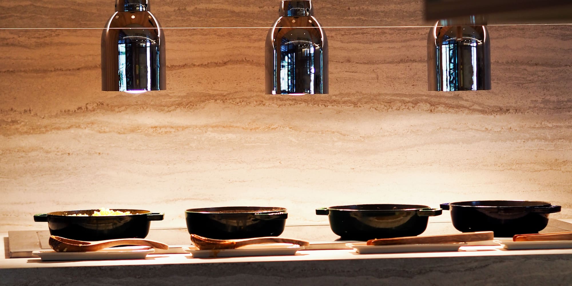 Buffet line with heat lamps, serving dishes, and stacked plates.