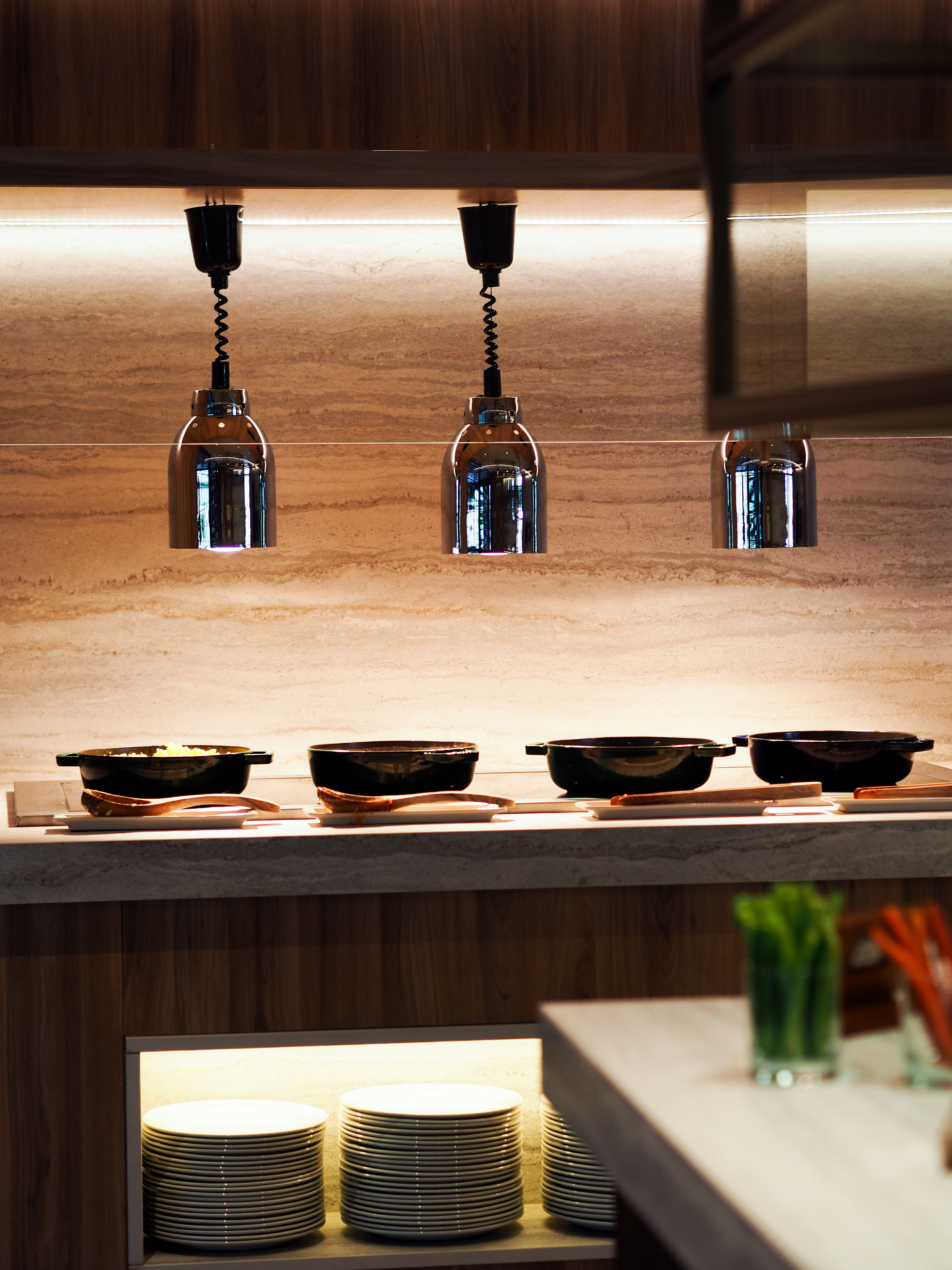 Buffet line with heat lamps, serving dishes, and stacked plates.