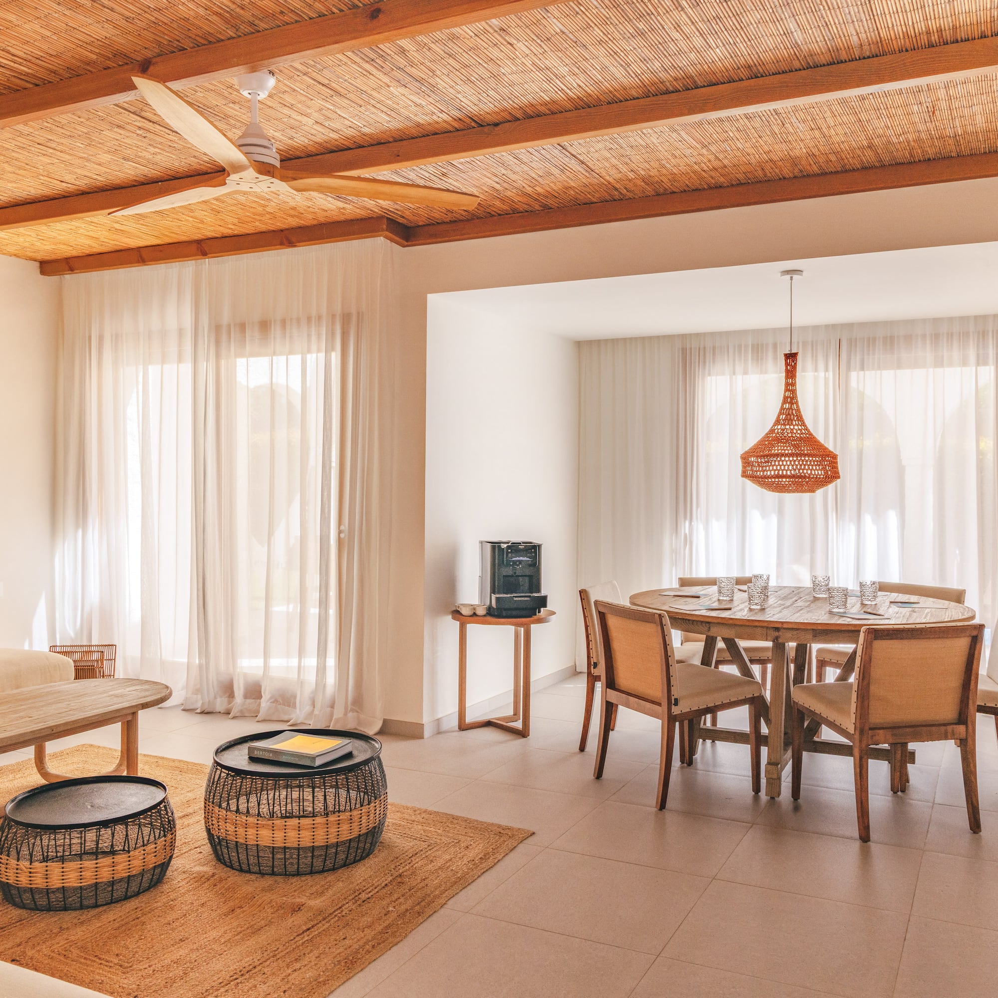 Tropical living and dining area with bamboo ceiling, rattan furniture, and macrame.