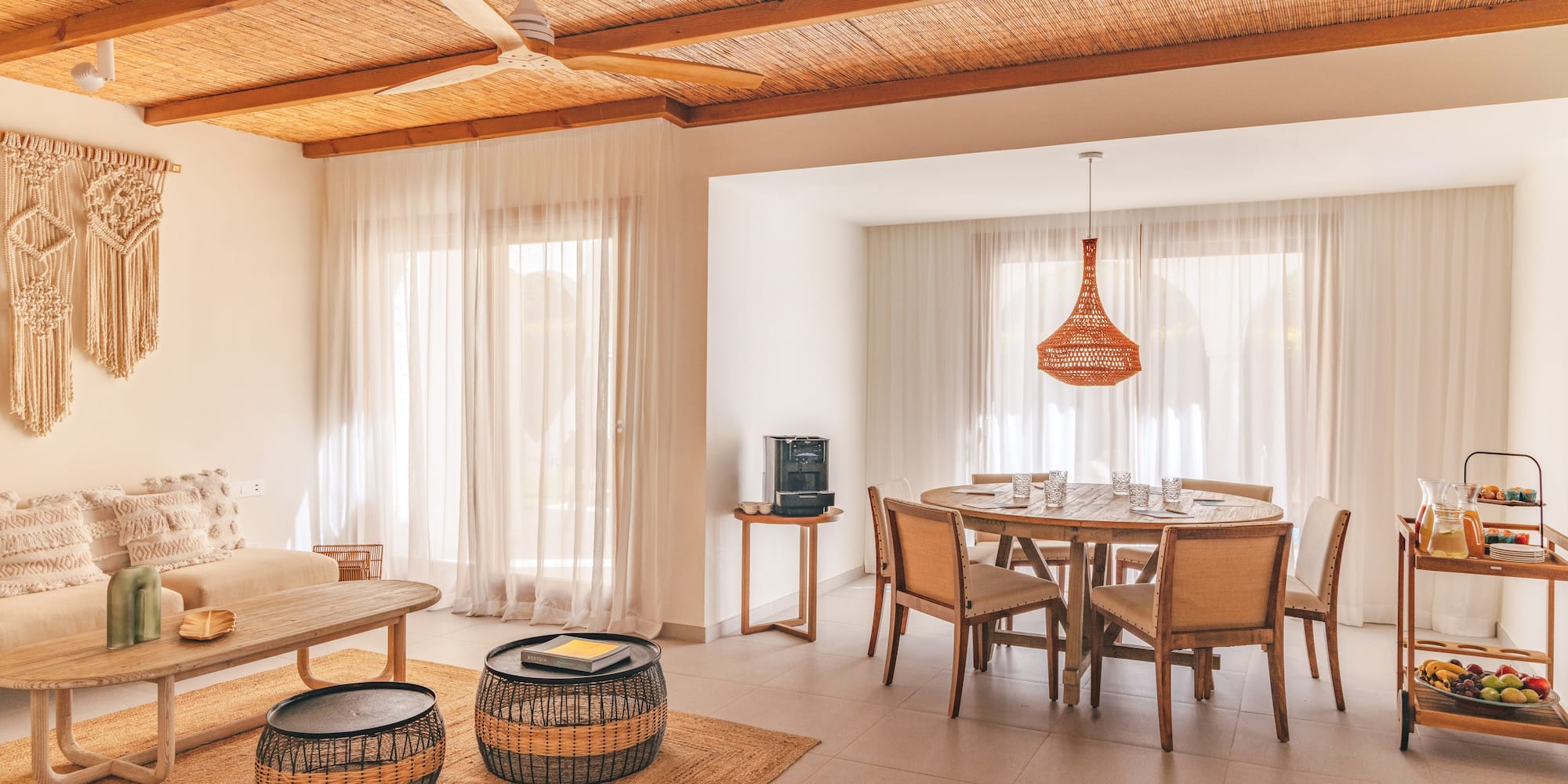 Tropical living and dining area with bamboo ceiling, rattan furniture, and macrame.