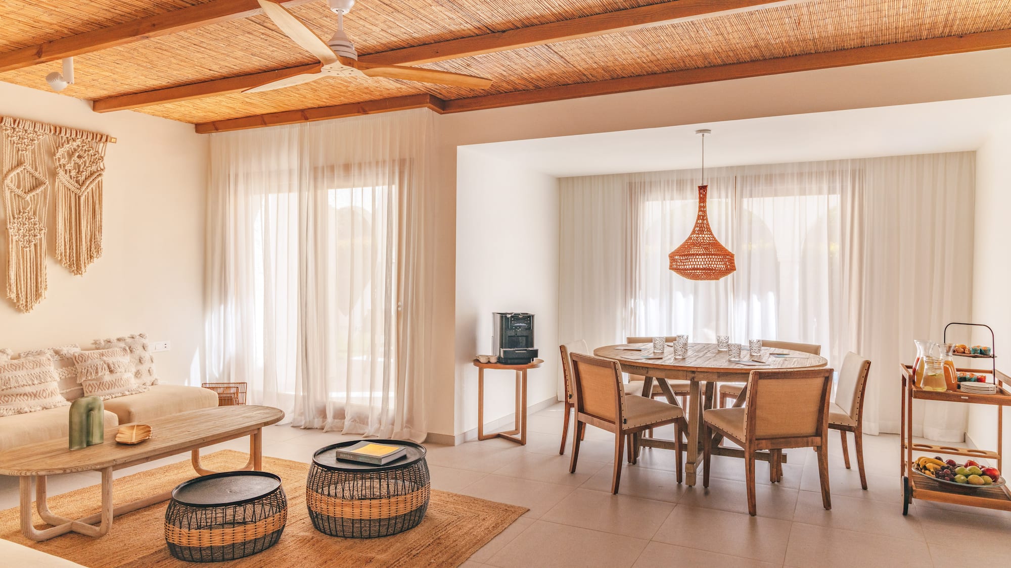 Tropical living and dining area with bamboo ceiling, rattan furniture, and macrame.