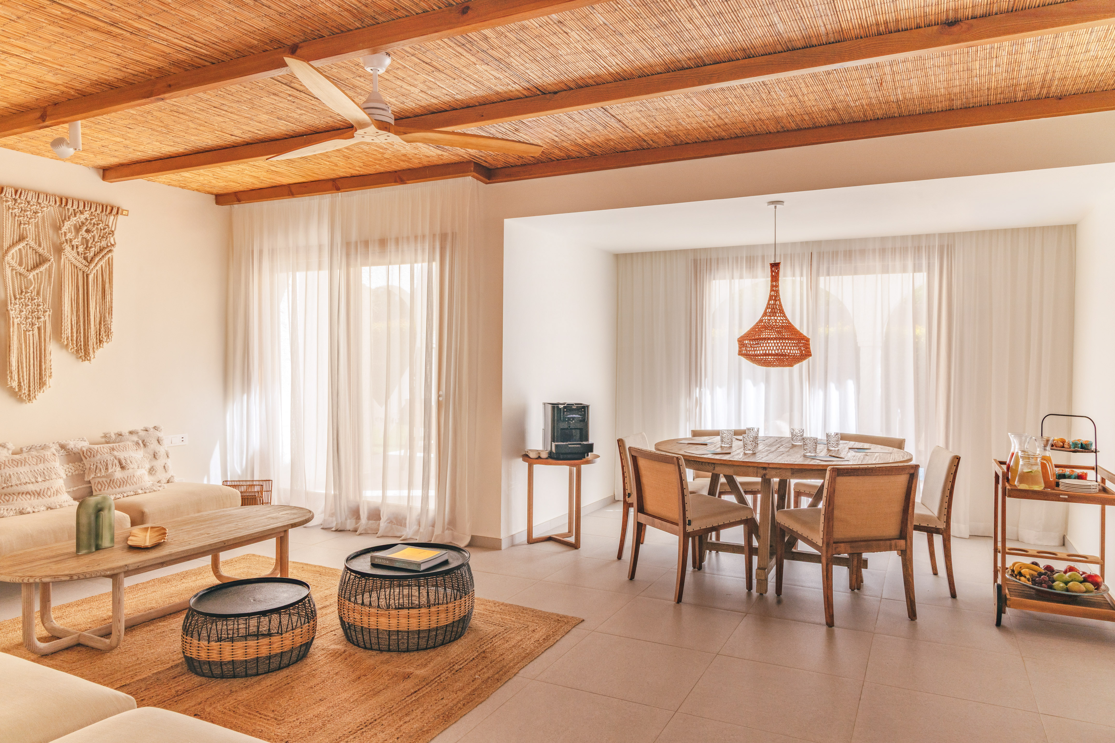 Tropical living and dining area with bamboo ceiling, rattan furniture, and macrame.