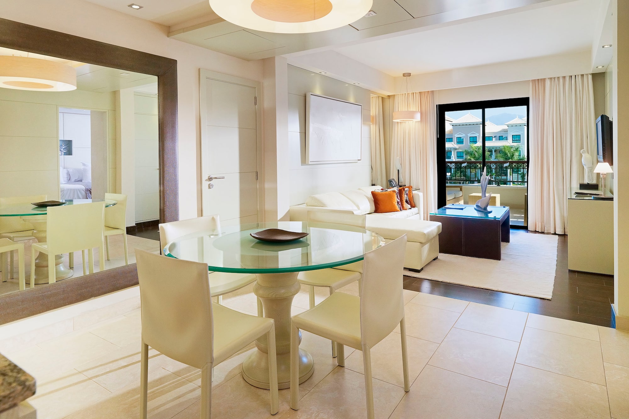 Modern hotel suite living and dining room with white sofa and balcony view.