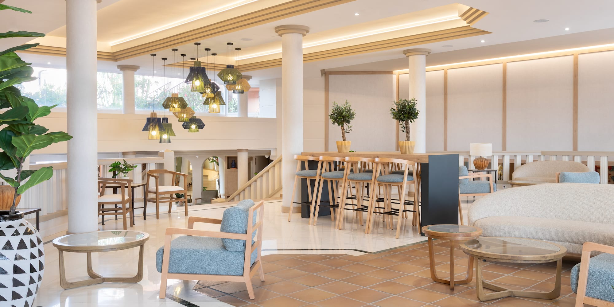 Modern hotel lobby with lounge seating, bar area, and stylish decorative lights.