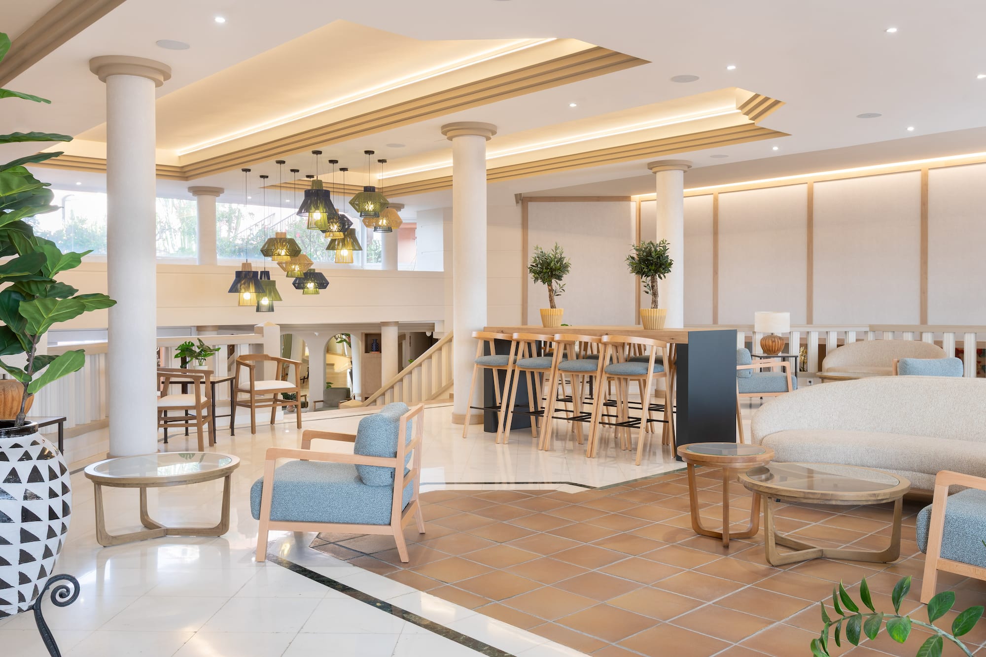 Modern hotel lobby with lounge seating, bar area, and stylish decorative lights.