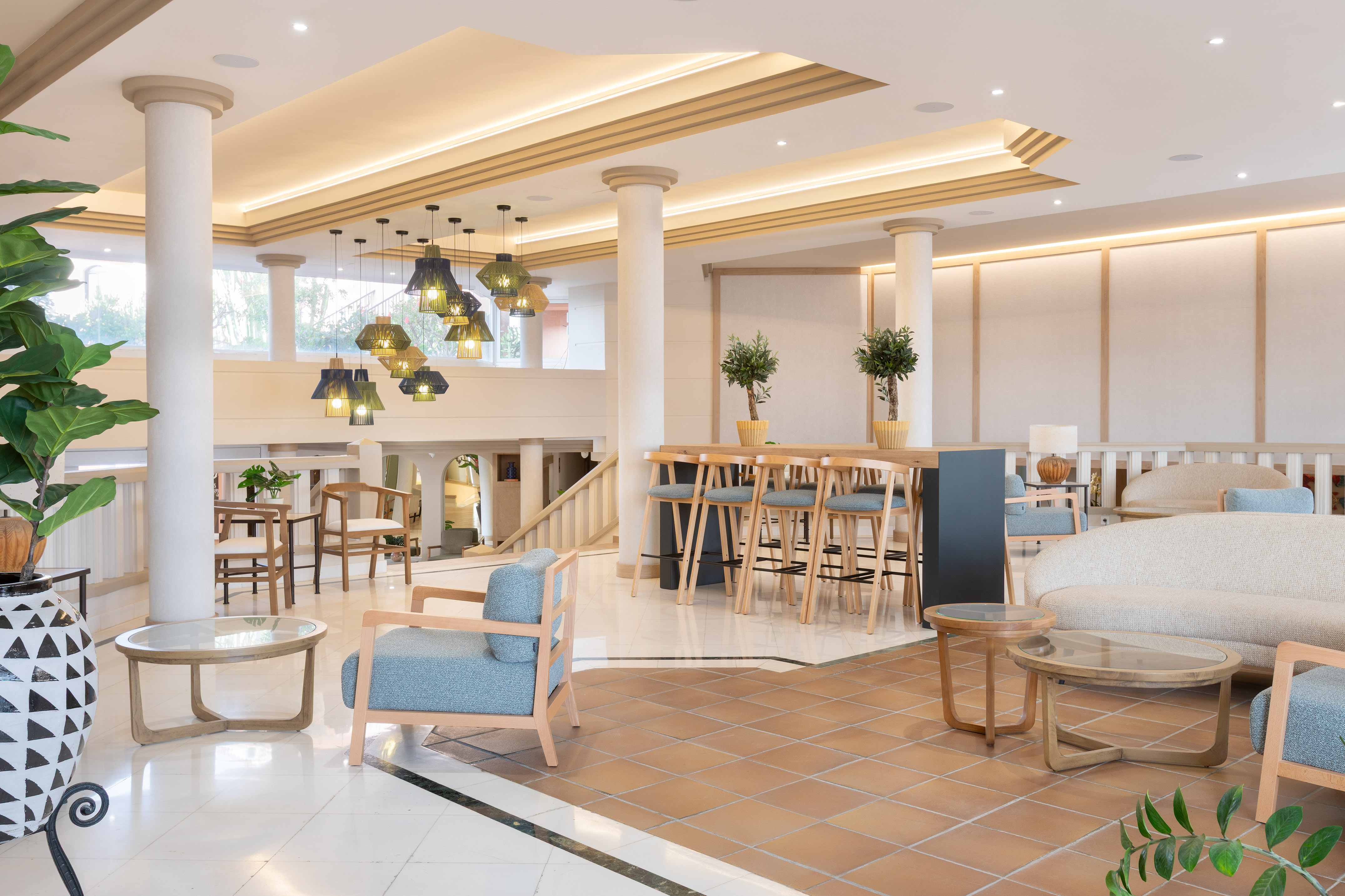 Modern hotel lobby with lounge seating, bar area, and stylish decorative lights.