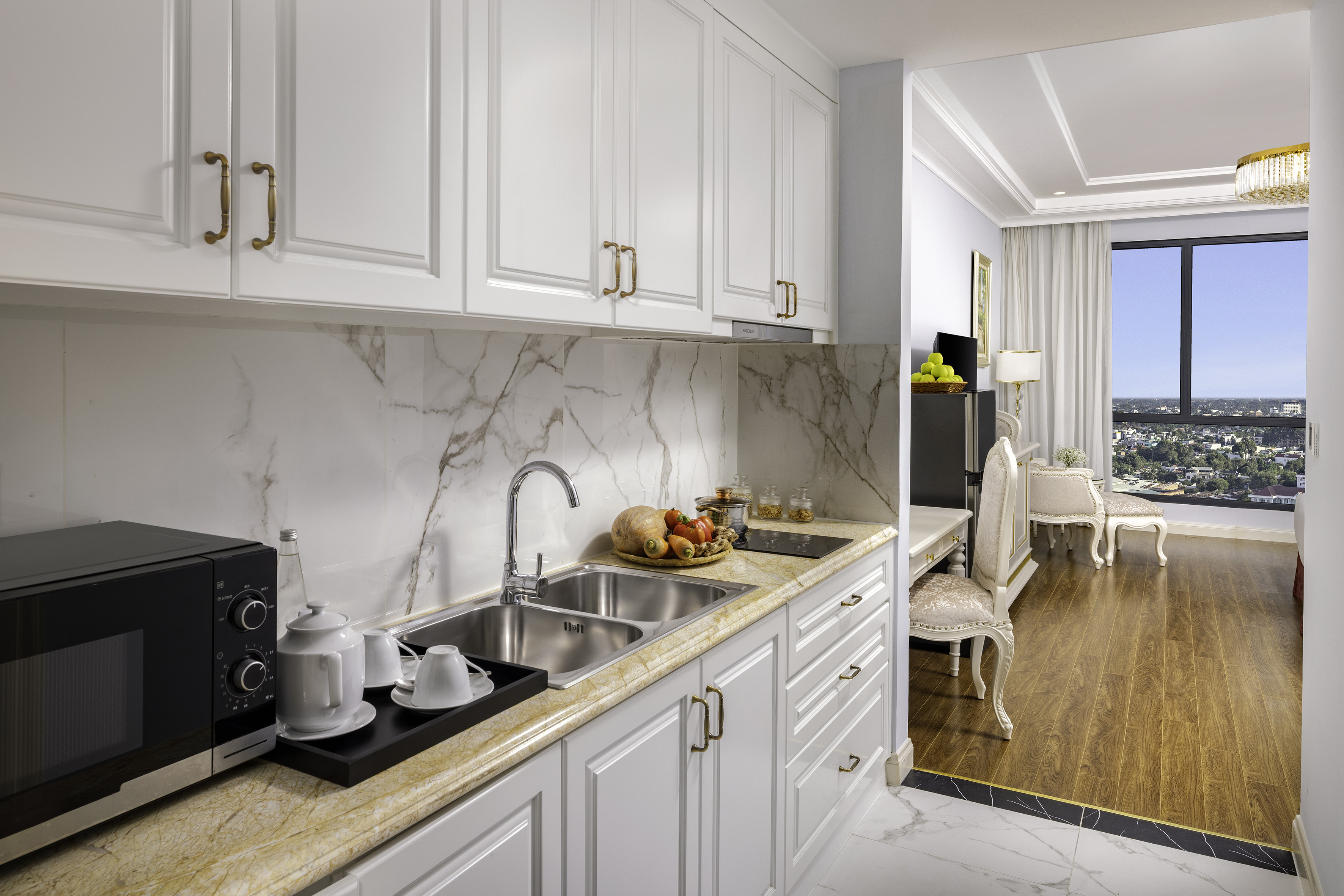 Modern apartment kitchen, white cabinets, marble backsplash, city view.