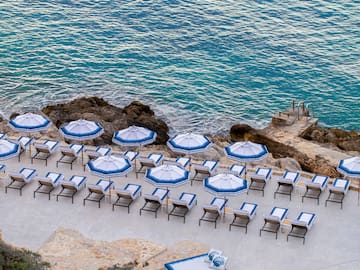 a pool with umbrellas and chairs on a rocky beach