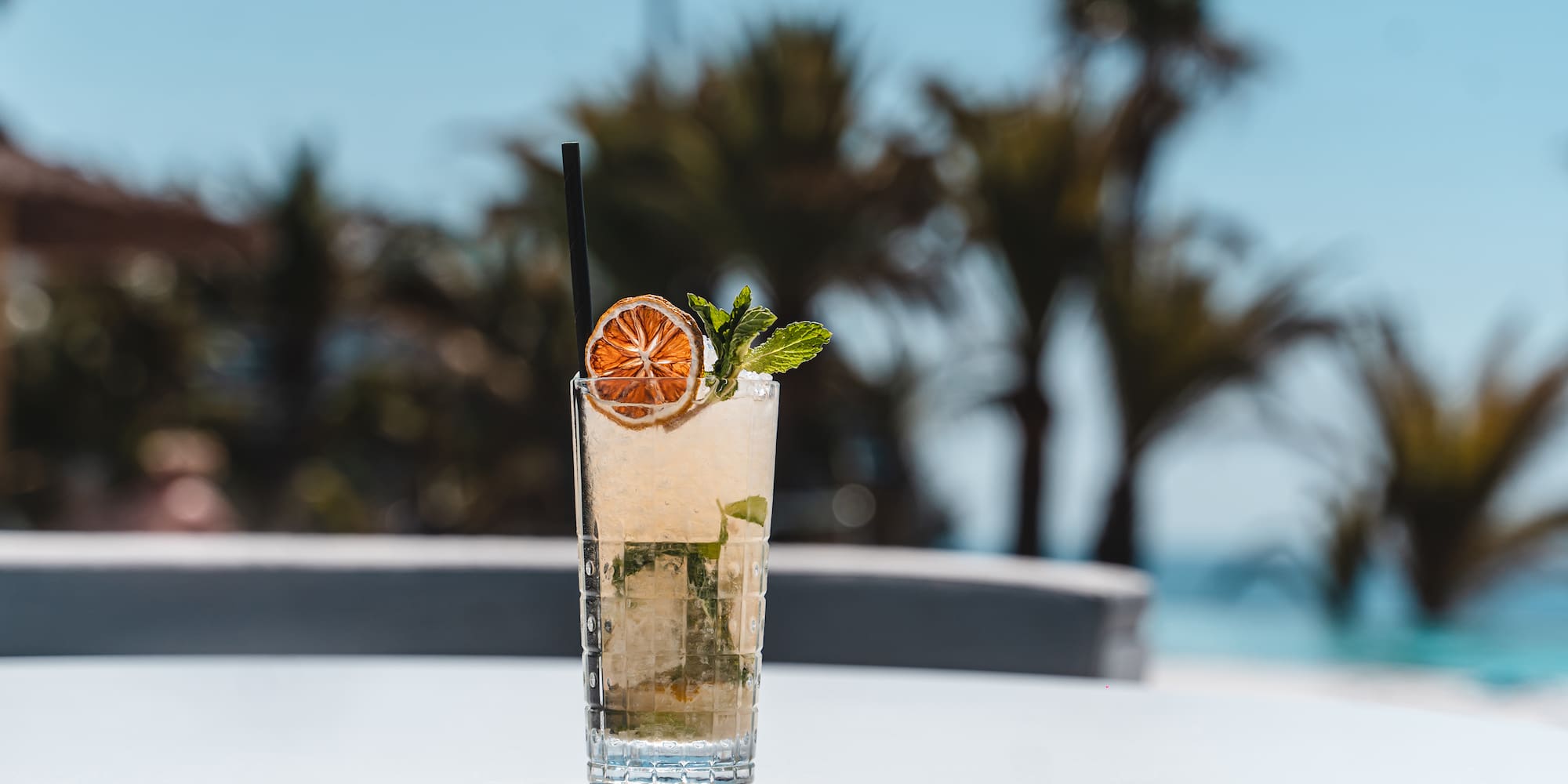 a glass of drink with a straw and a slice of orange on top