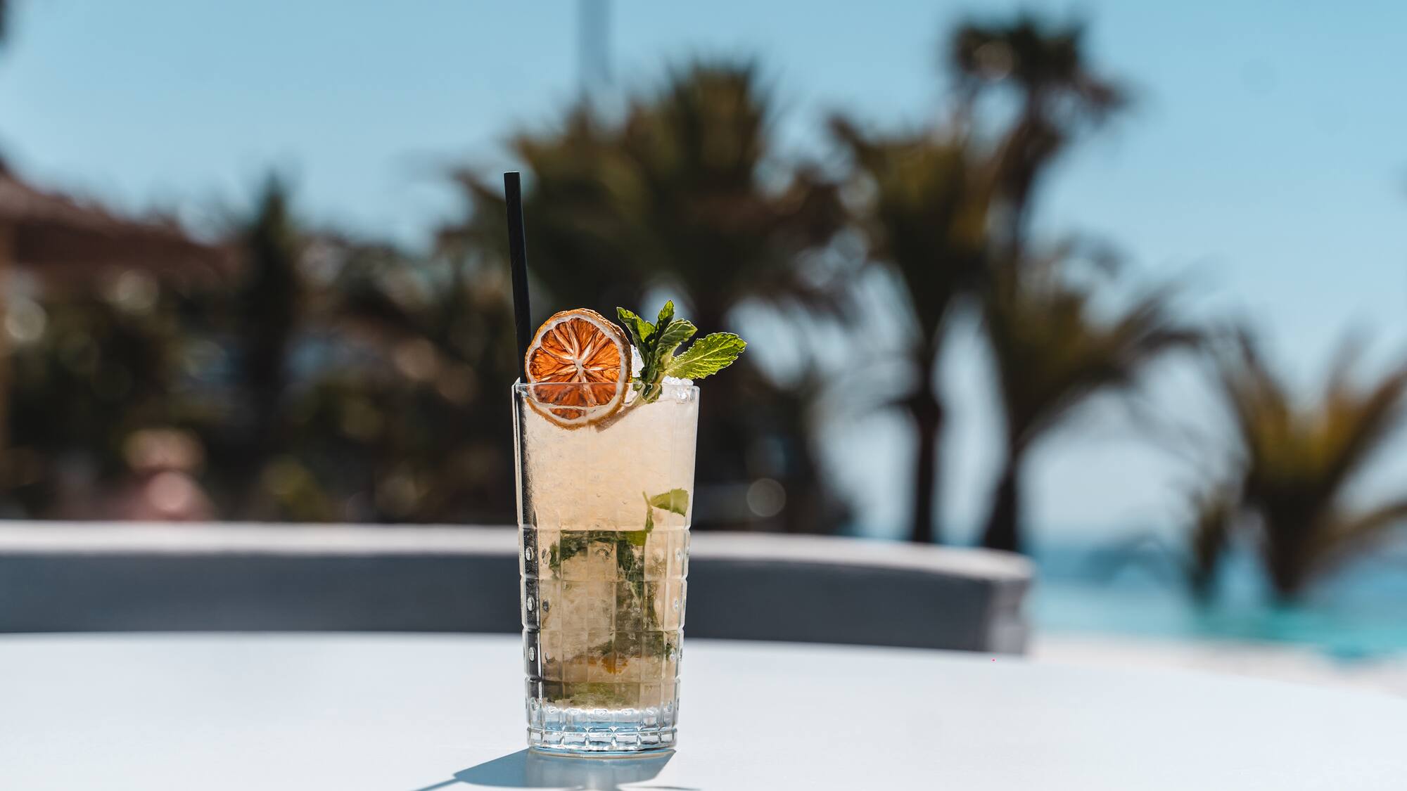 a glass of drink with a straw and a slice of orange on top