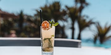 a glass of drink with a straw and a slice of orange on top