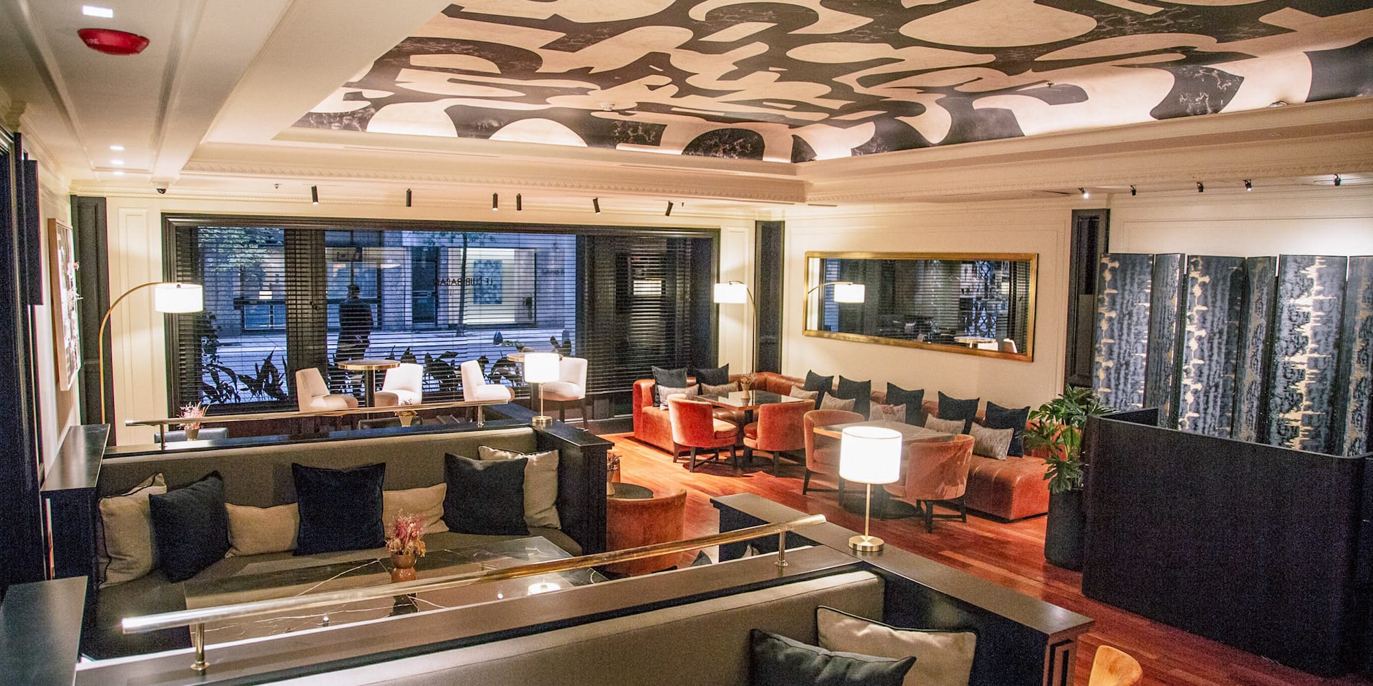 Lounge de hotel moderno con sofás, sillones y techo de diseño abstracto.