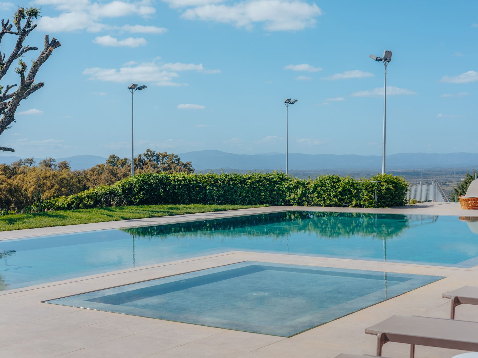 Outdoor swimming pool with hot tub, sun loungers, and scenic mountain view.