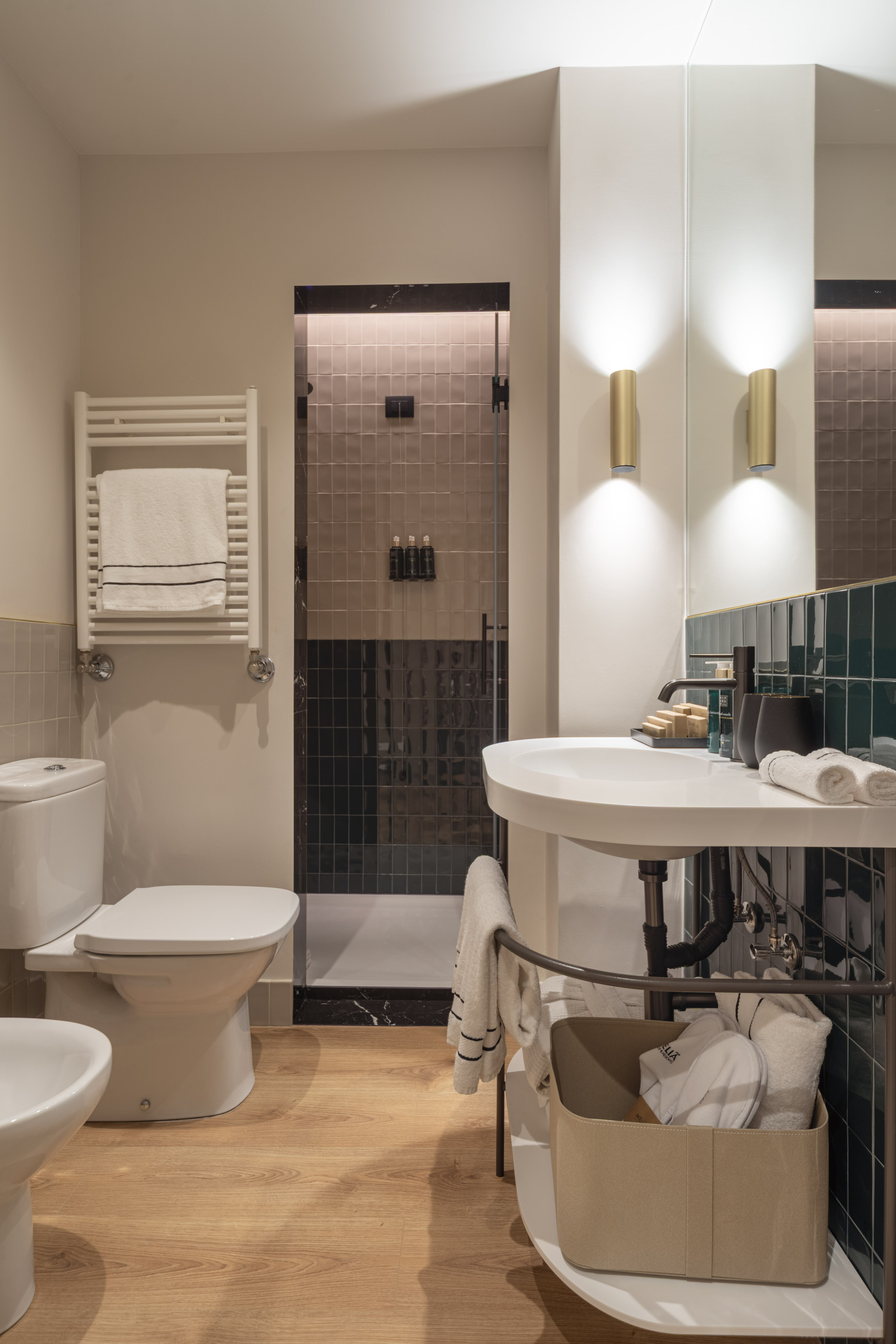 Modern bathroom with shower, toilet, sink, green tiles, and wood floor.