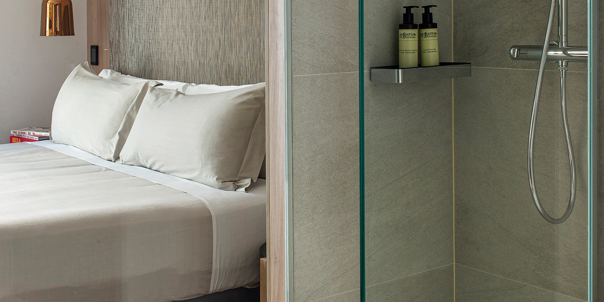 a shower with a glass door and a bed