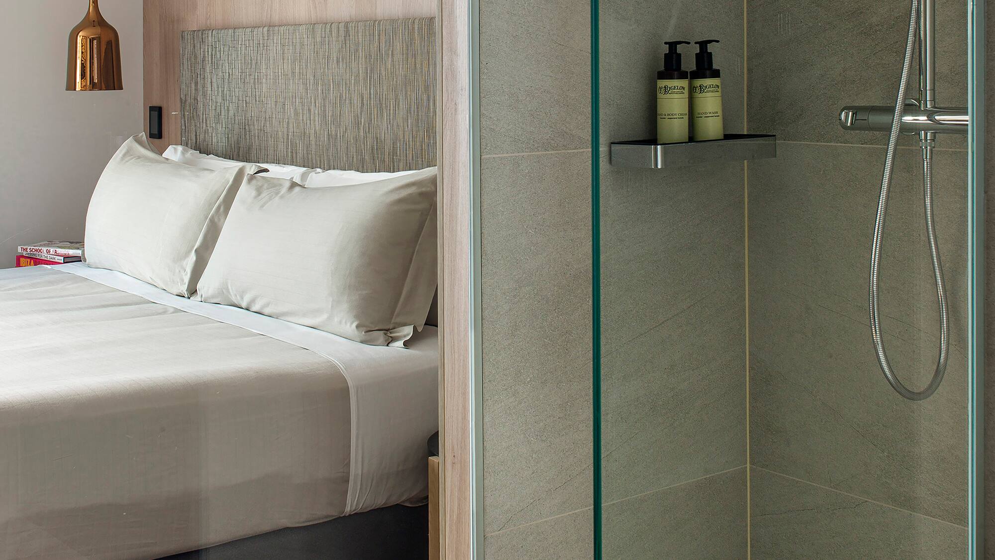 a shower with a glass door and a bed