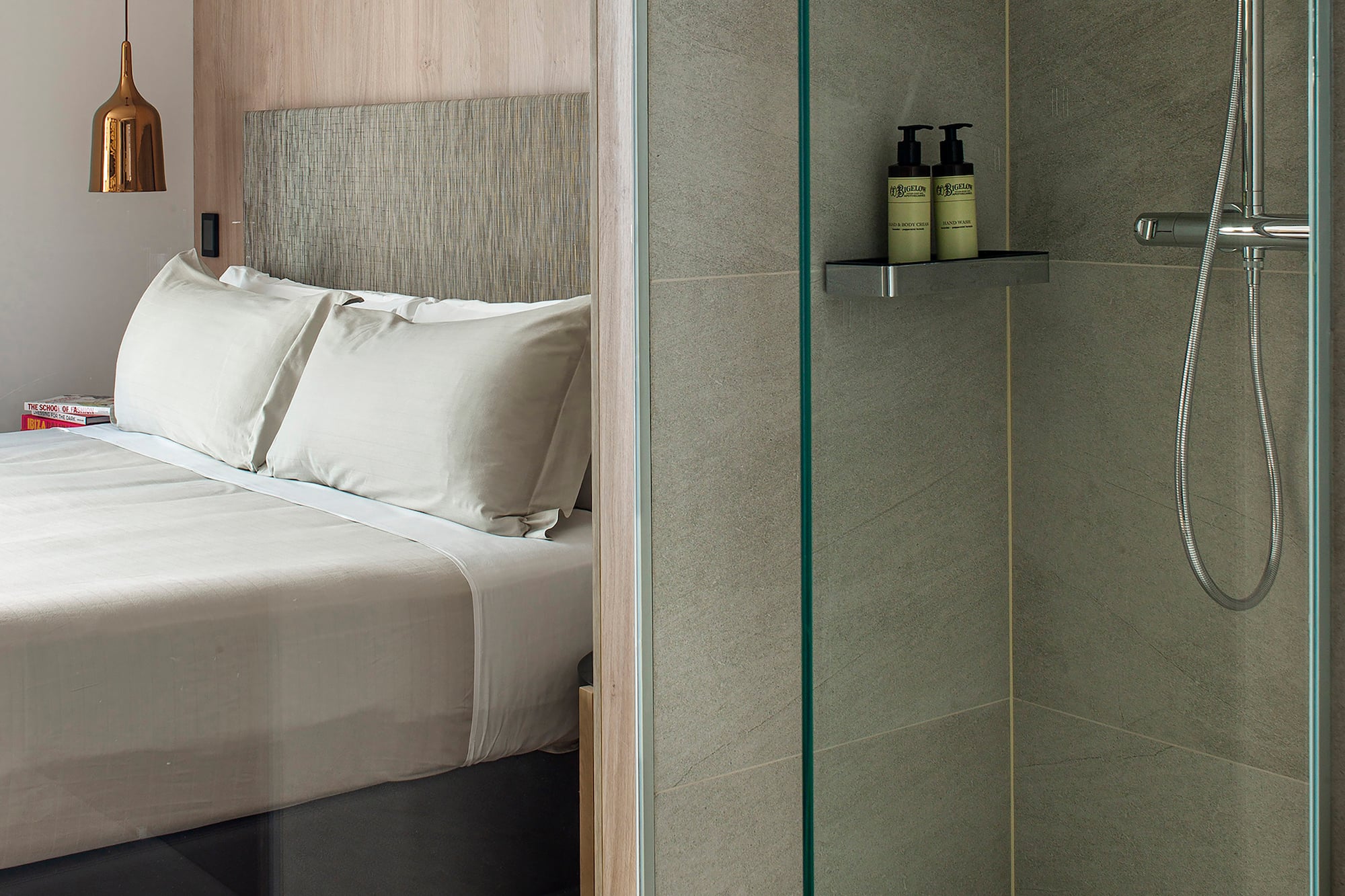 a shower with a glass door and a bed