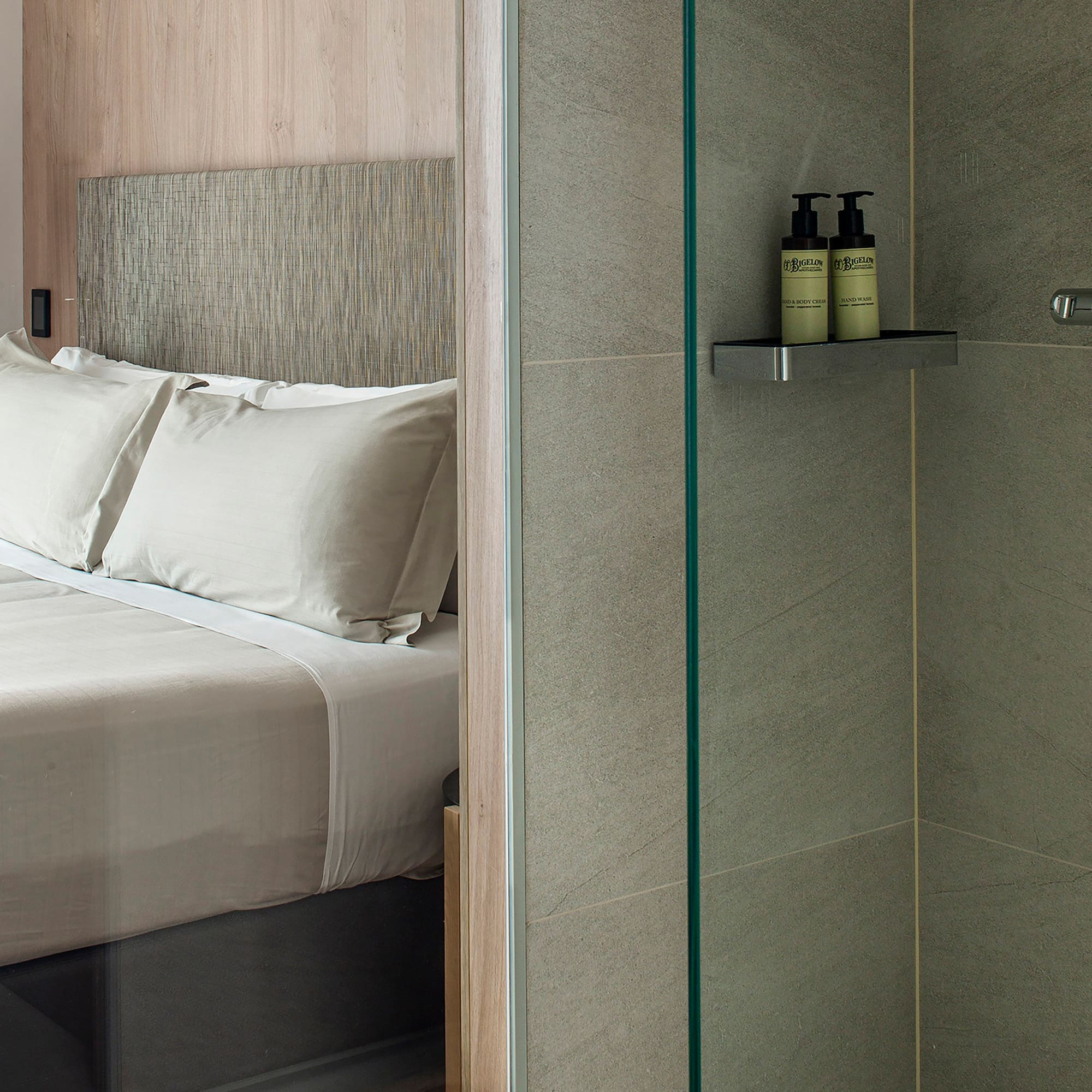a shower with a glass door and a bed