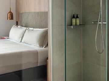 a shower with a glass door and a bed