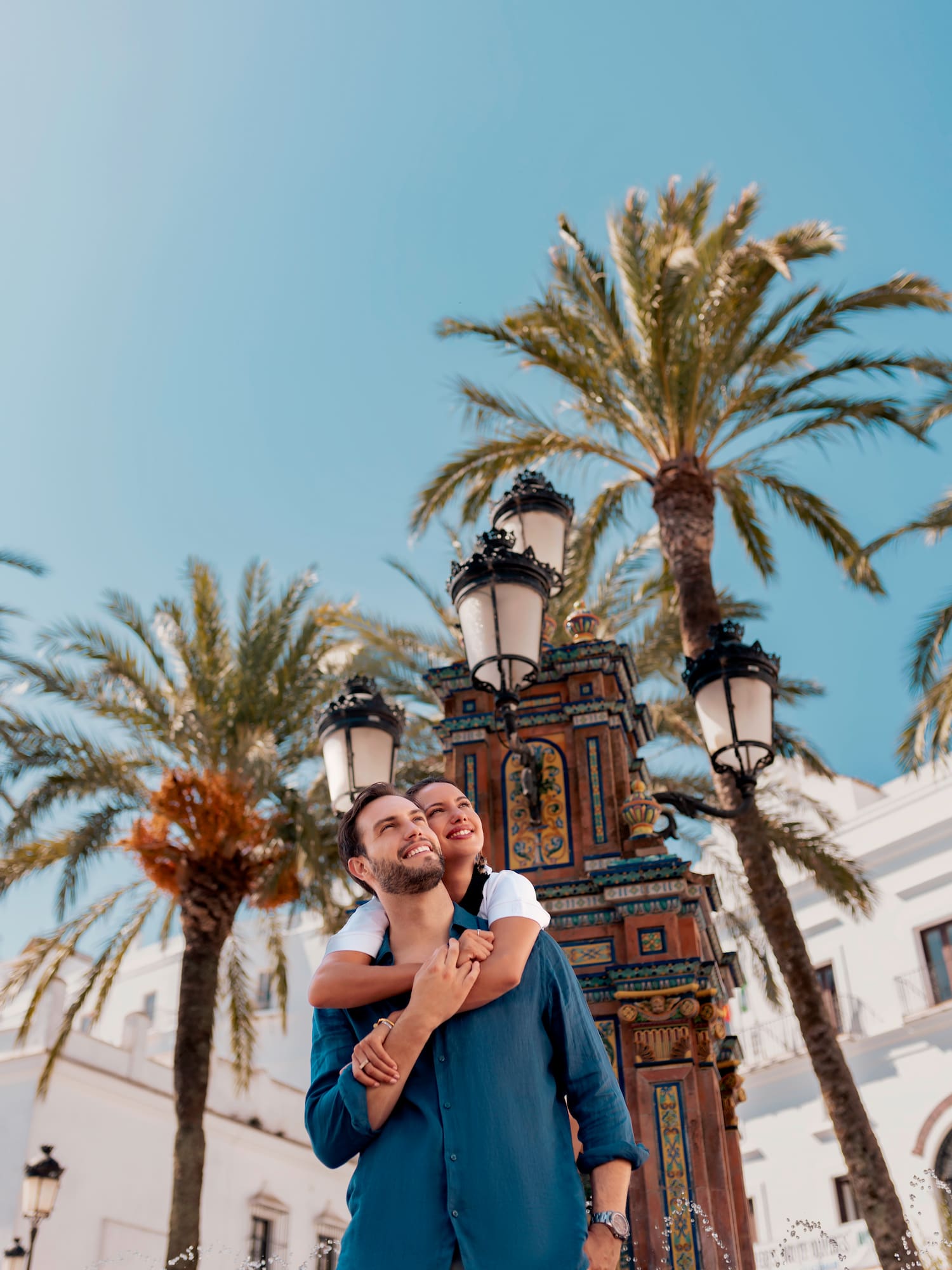 a man and woman hugging in front of palm trees
