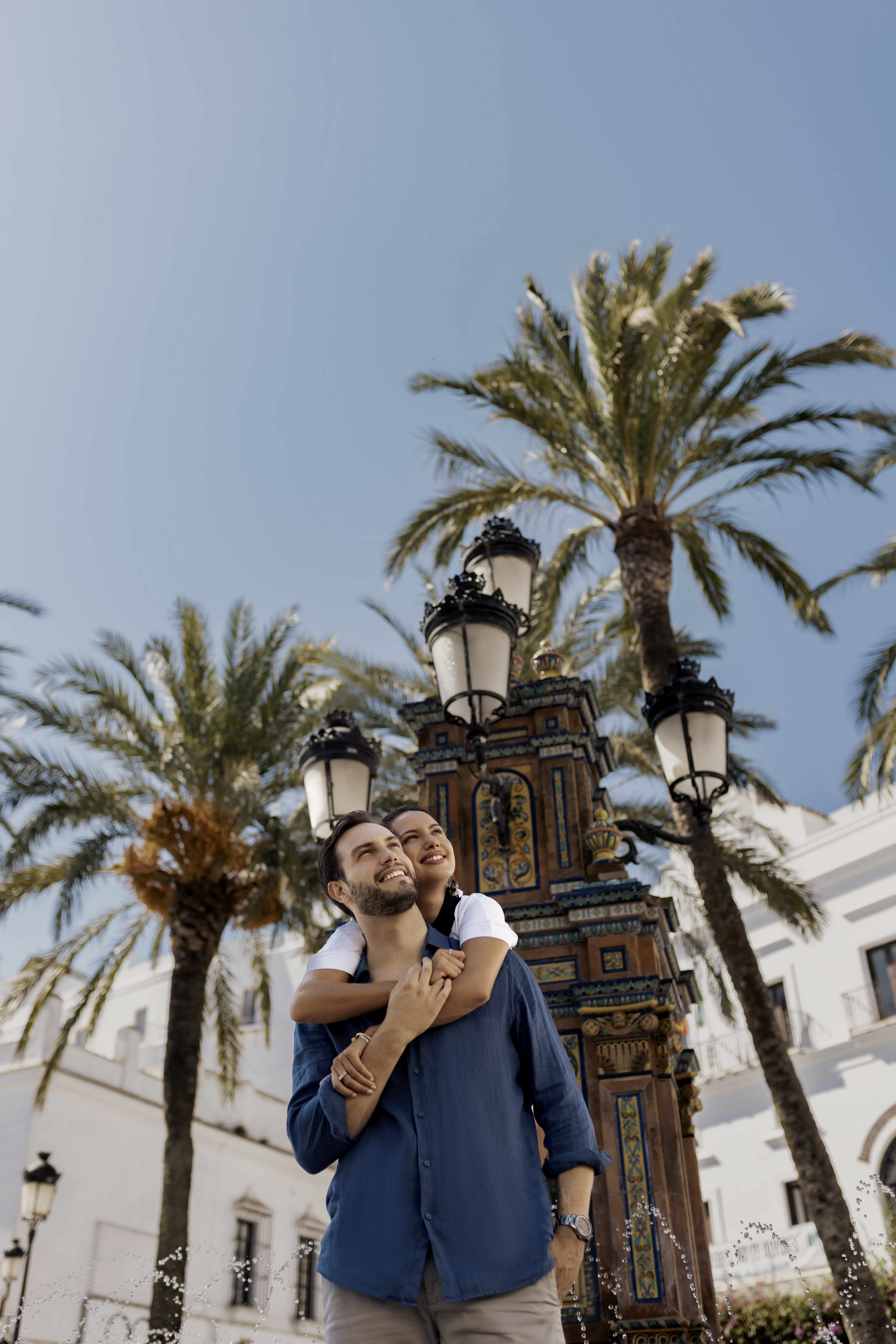 a man and woman hugging in front of palm trees