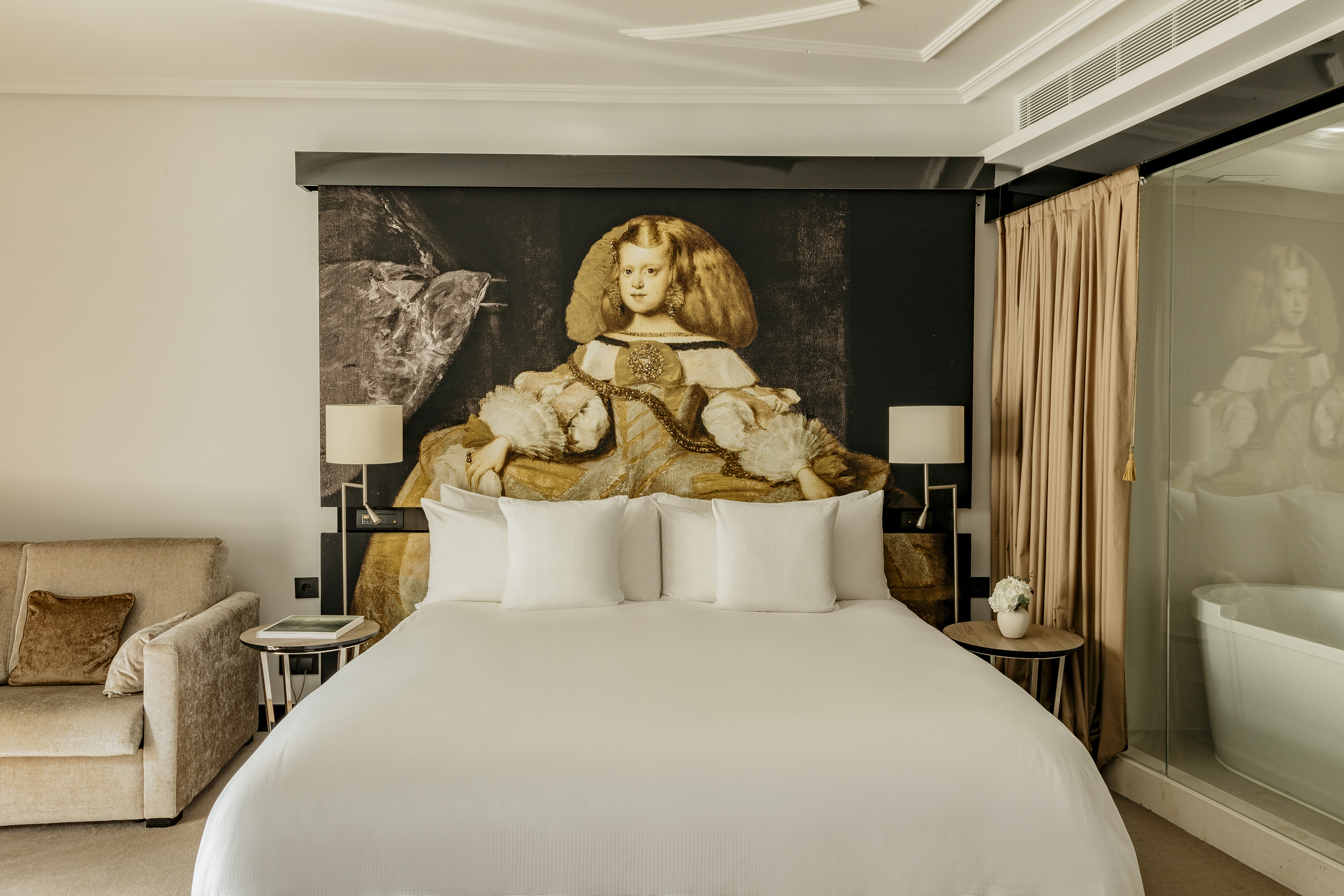 Modern hotel room with Velázquez Infanta portrait headboard and king bed.
