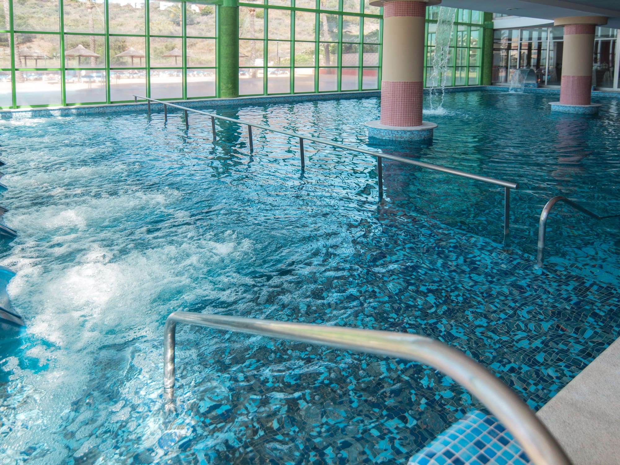 Piscina spa interior con chorros de hidromasaje y azulejos azules.